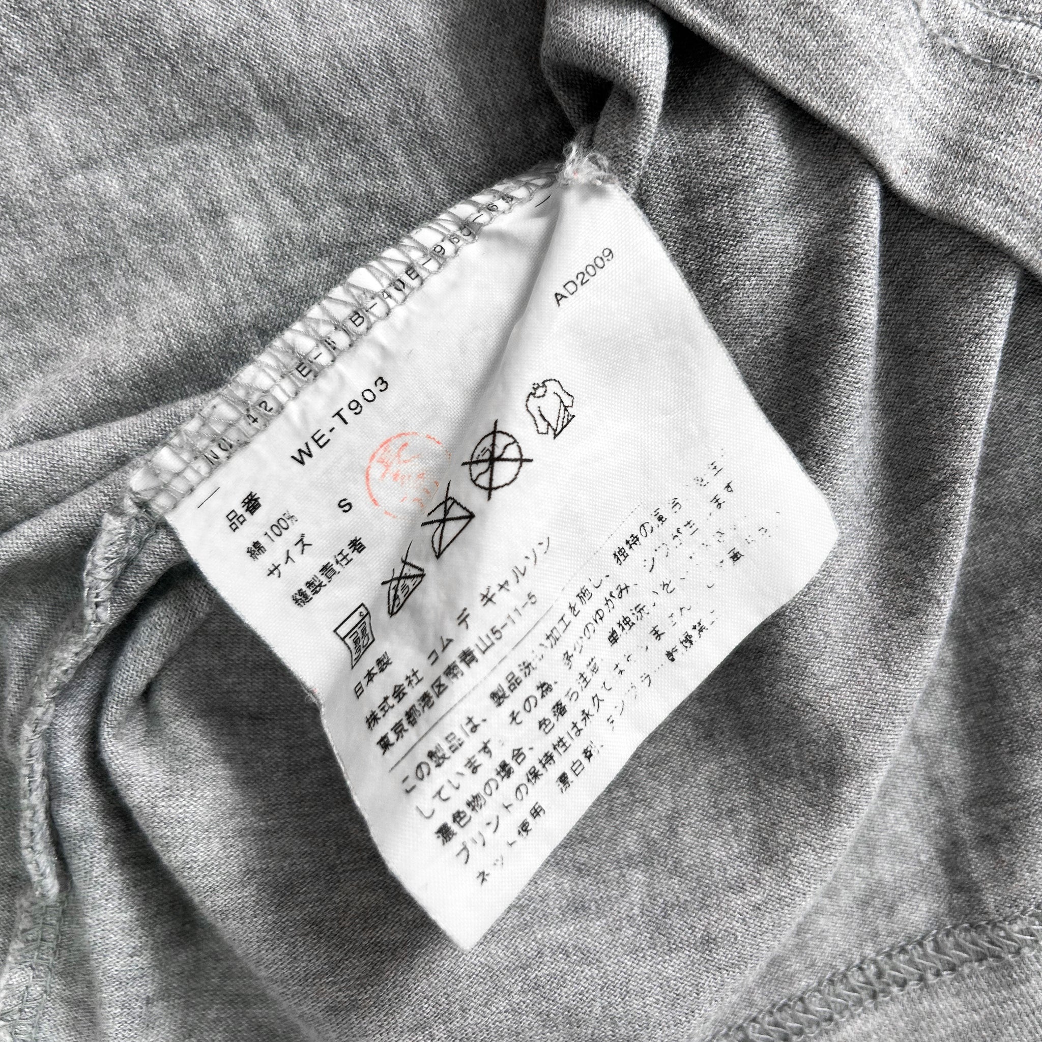 a close-up view of a white label with black text and symbols on a gray fabric background.