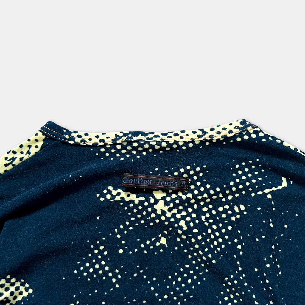 a close-up view of a dark blue shirt with a yellow polka dot pattern. There is a small black label on the shirt with text that reads "Gauffin Jeans".