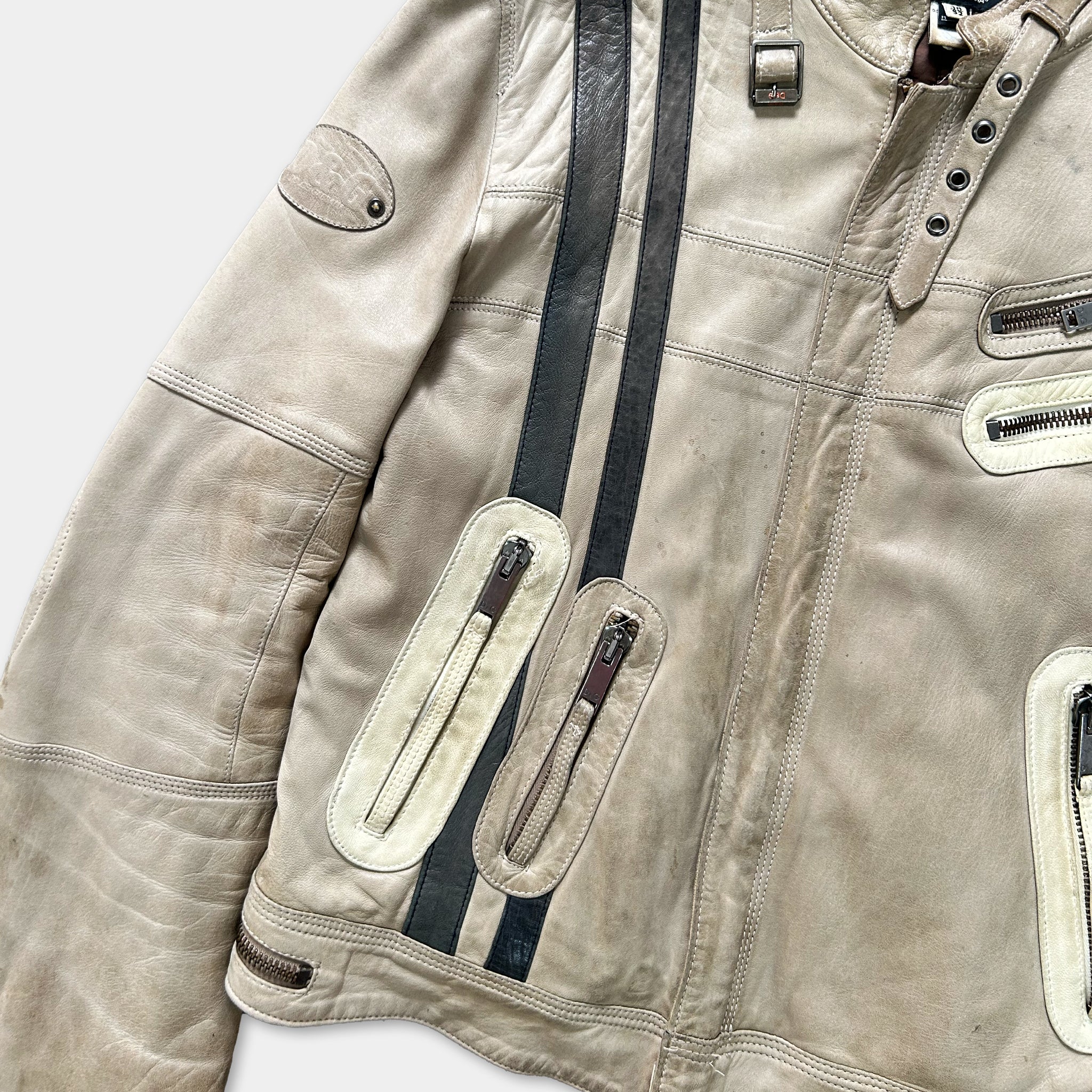A close-up view of a tan leather jacket with multiple pockets and zippers.