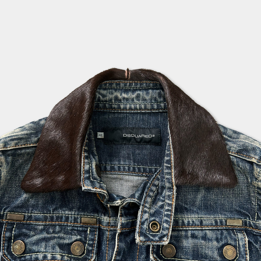 A denim jacket with a brown fur collar, a black label on the collar, and a zipper.