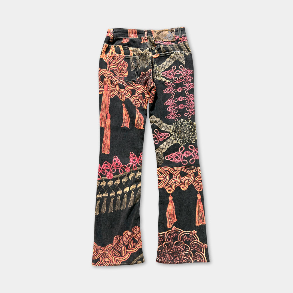 A pair of black jeans with a vibrant, colorful, and intricate printed design on the front.
