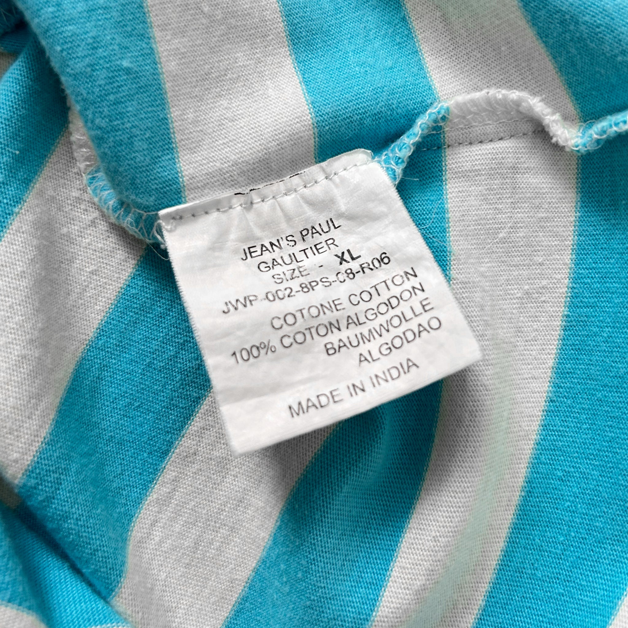 a close-up view of a white label attached to a striped fabric, with text indicating the size and material of the garment.