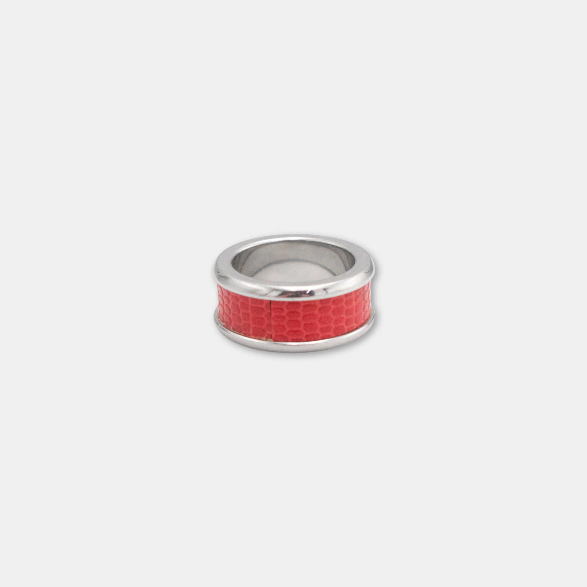 A silver ring with a red, snake-like pattern on the band.