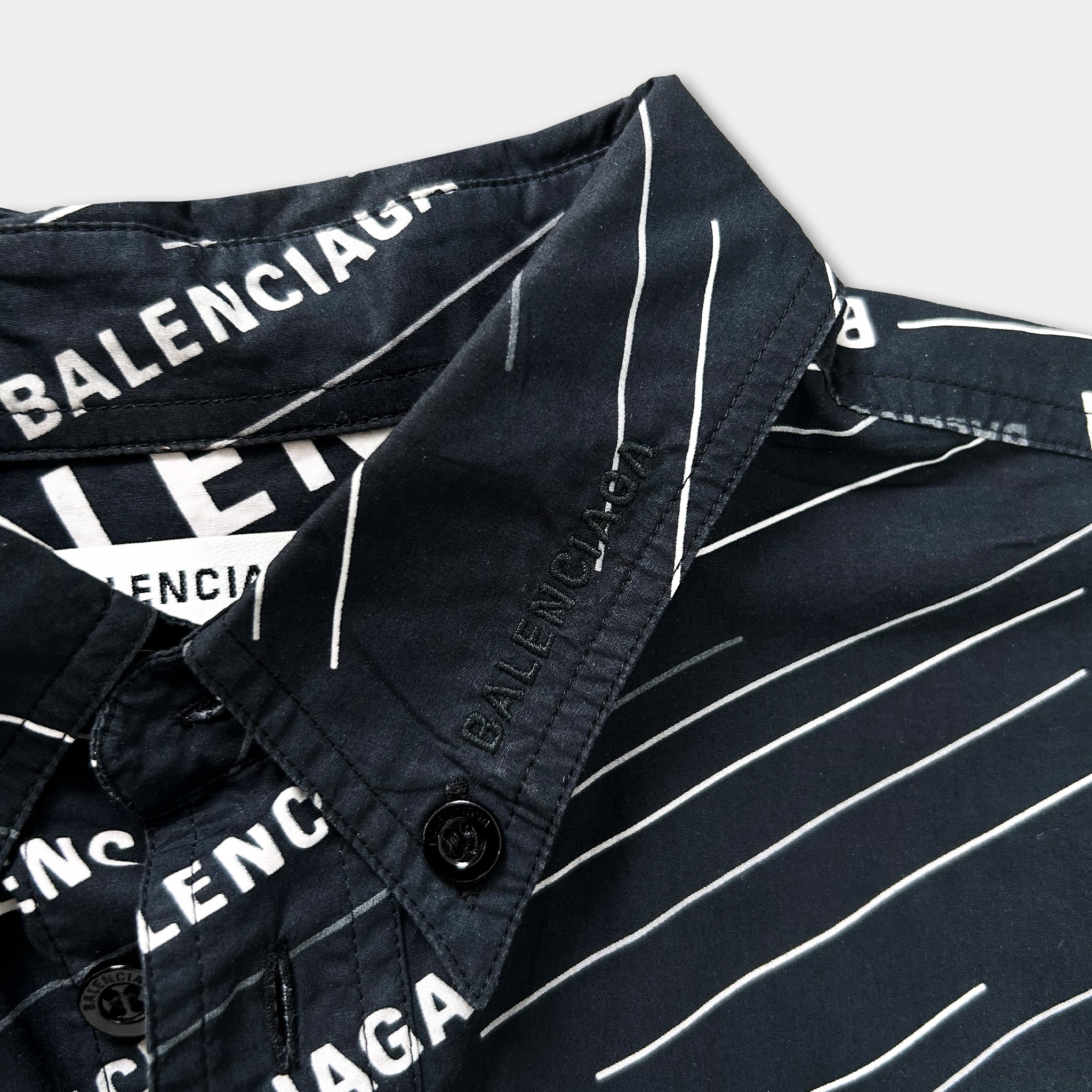 a close-up view of a black and white striped shirt collar, with the brand name "BALENCIA" printed on it.