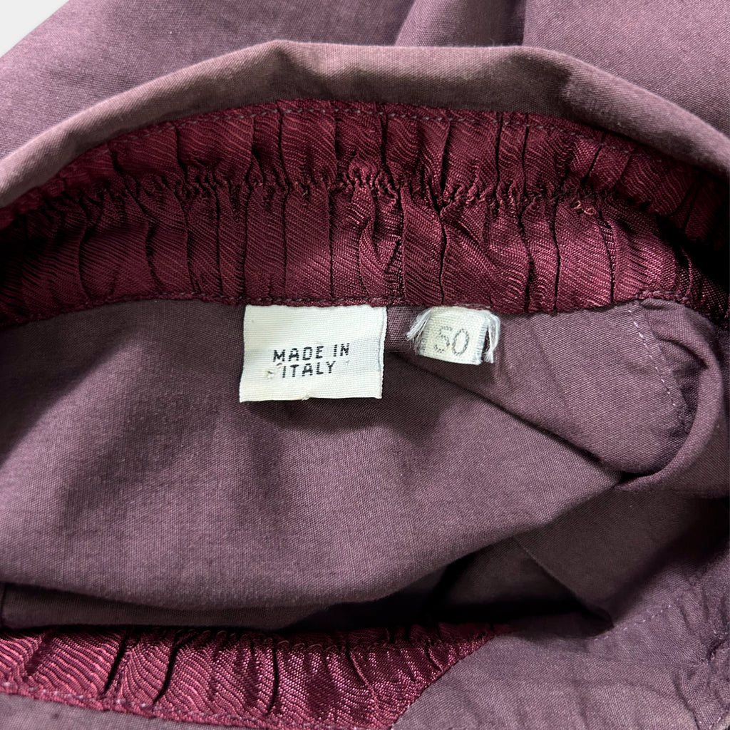 a close-up view of a purple fabric, possibly a garment or textile, with a label indicating that it is made in Italy.