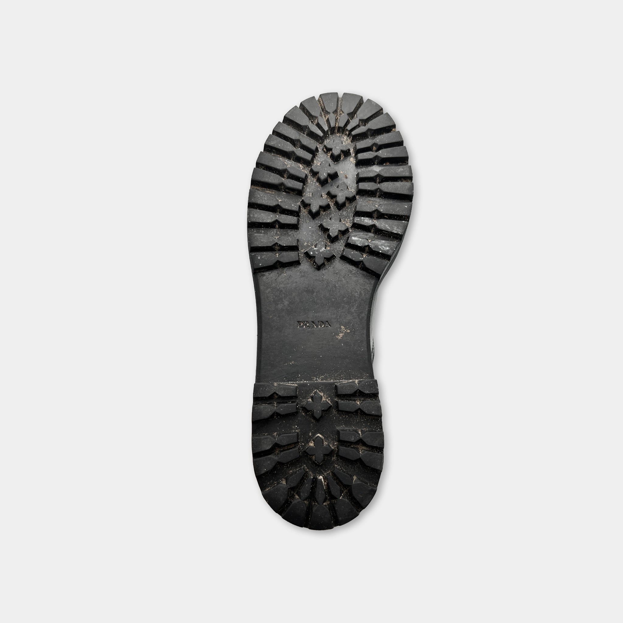 A close-up view of a black rubber sole of a shoe against a white background.