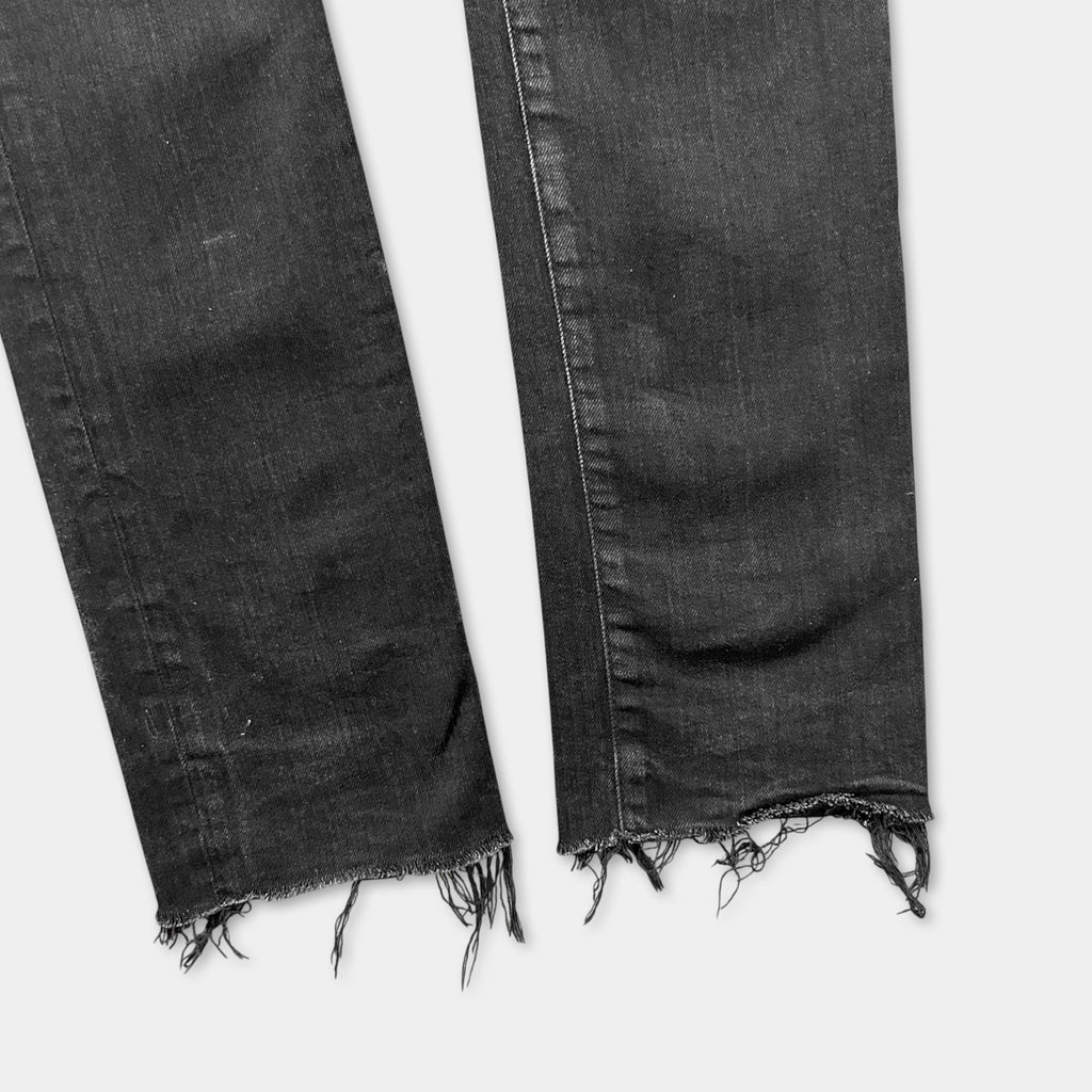 a pair of black jeans with frayed edges and torn fabric, indicating wear and tear.