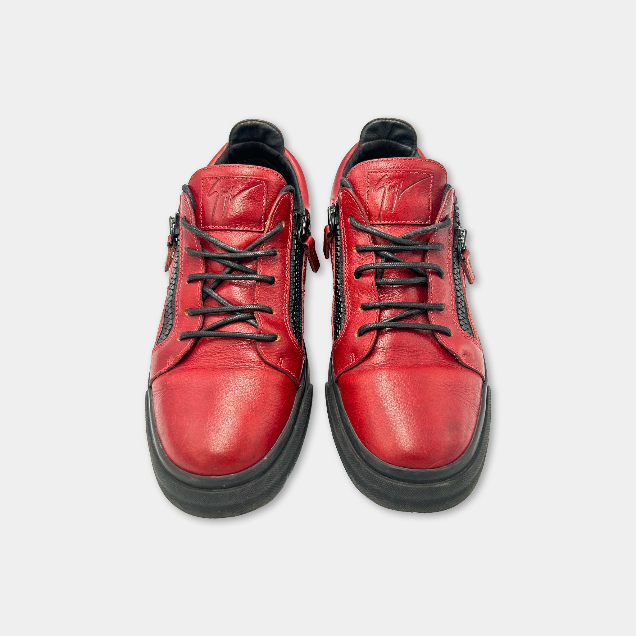 A pair of red leather sneakers with black zippers and laces.