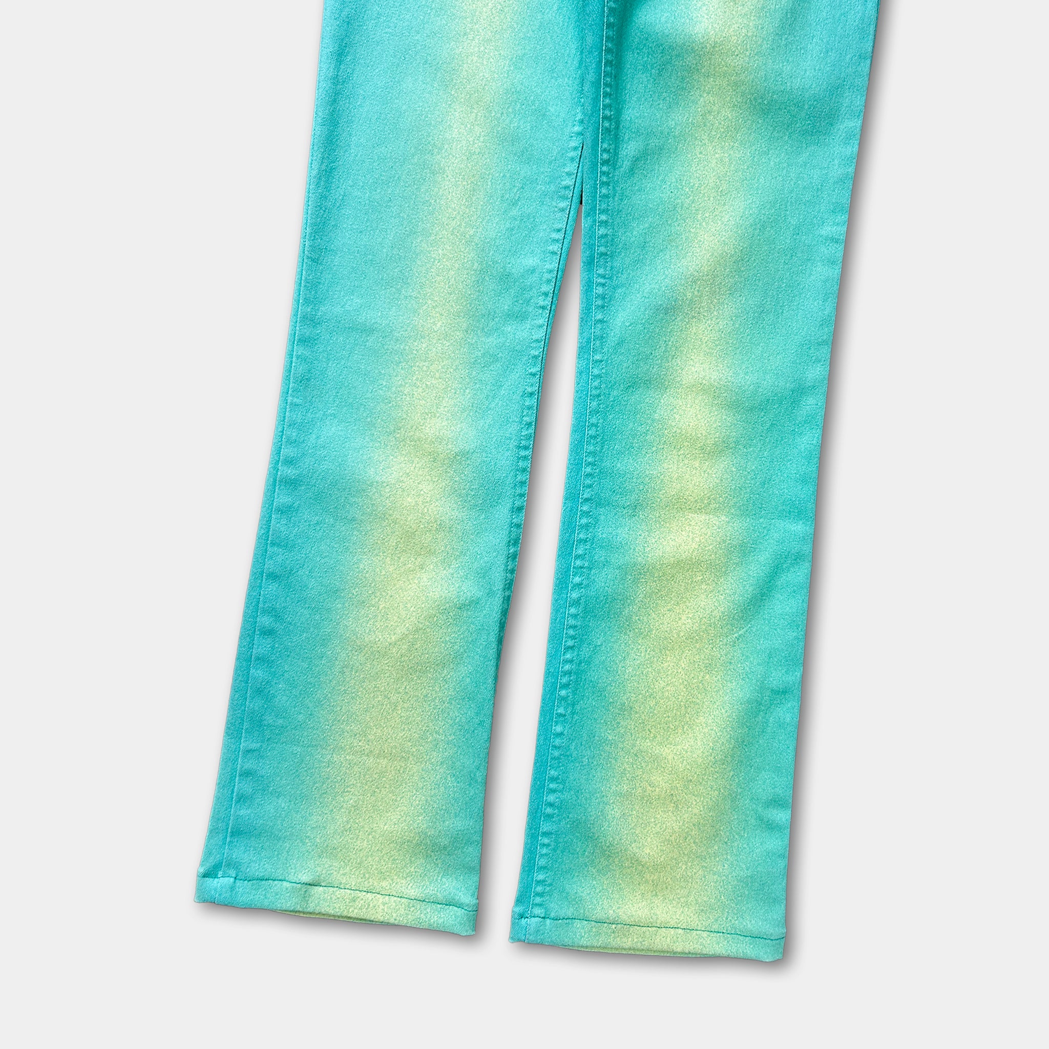 A pair of turquoise-colored jeans with a yellow-green gradient pattern.