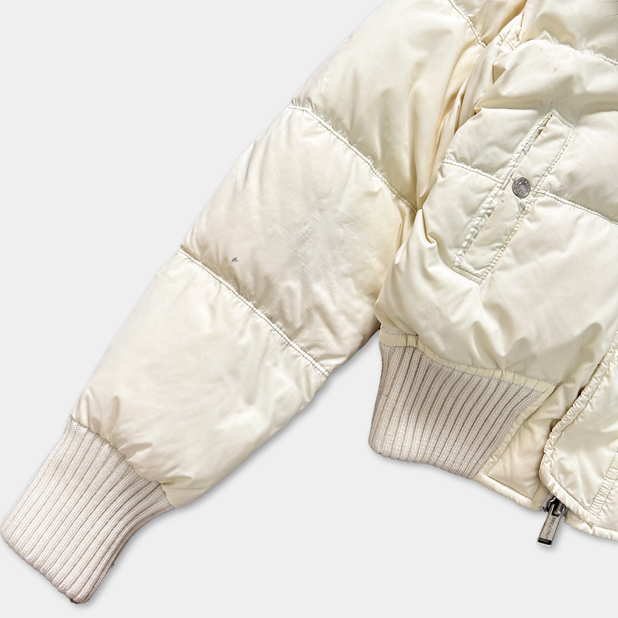 A close-up view of a white puffy jacket with a zipper and a white sleeve.