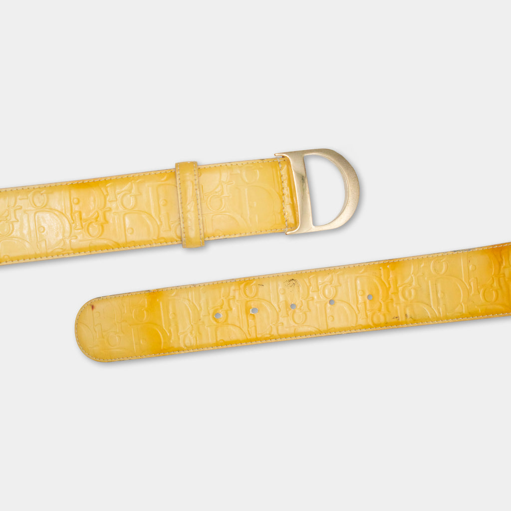 A yellow belt with a Dior logo embossed on it, featuring a buckle and a row of holes.