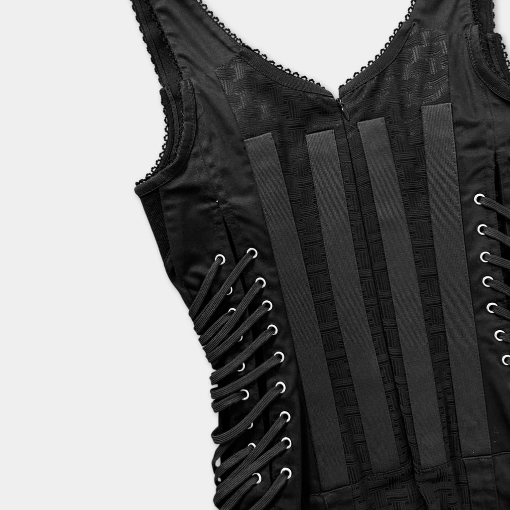 A close-up view of a black corset with intricate lace-up details.