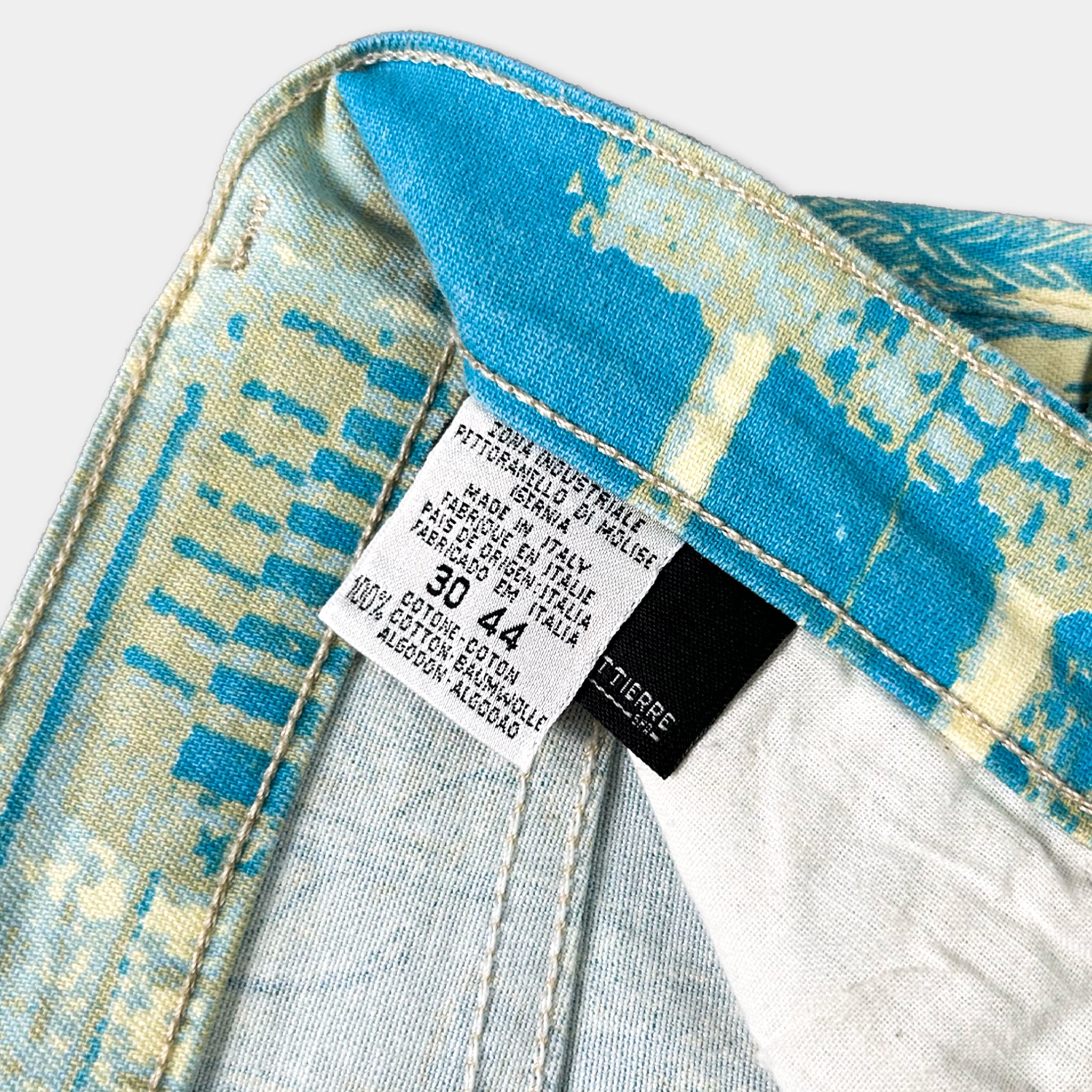 a close-up view of a label on a pair of blue jeans, with a patterned fabric visible.