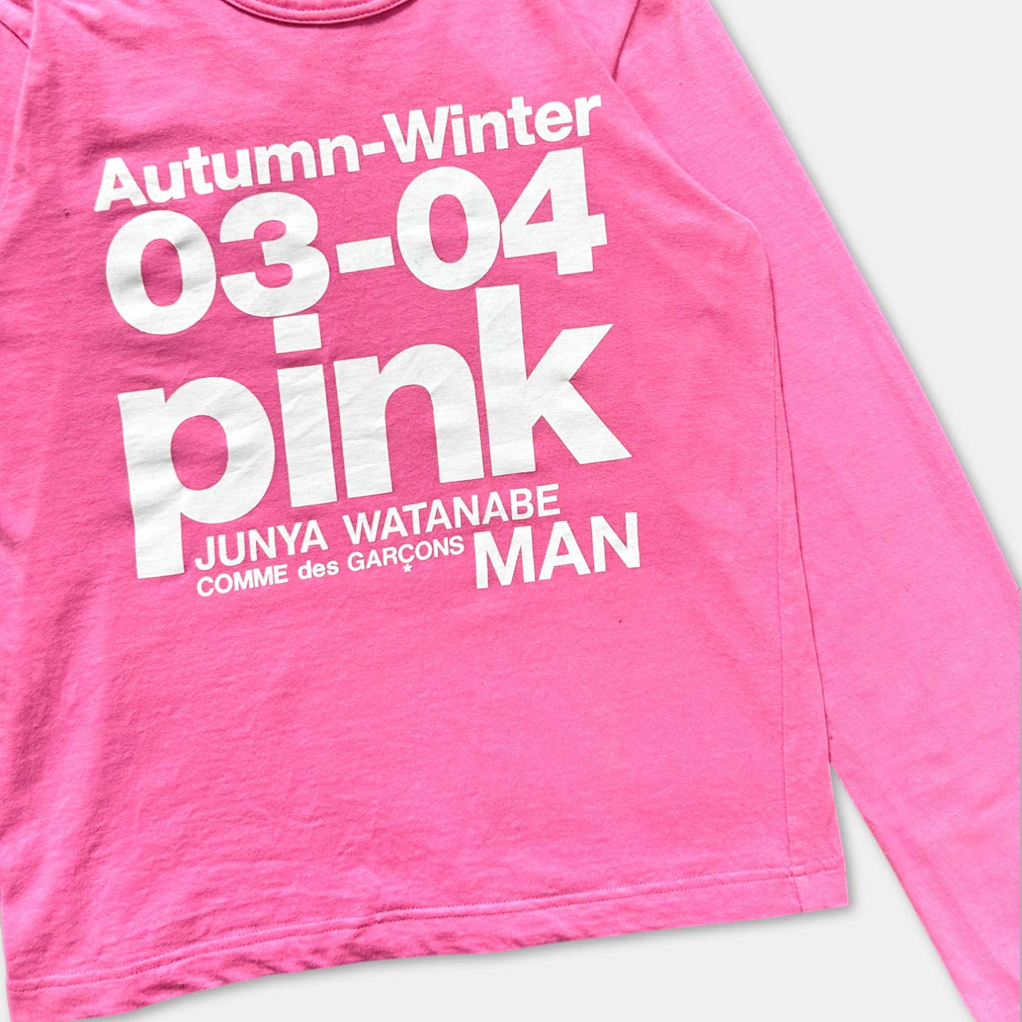 A pink long-sleeved shirt with white text printed on it.