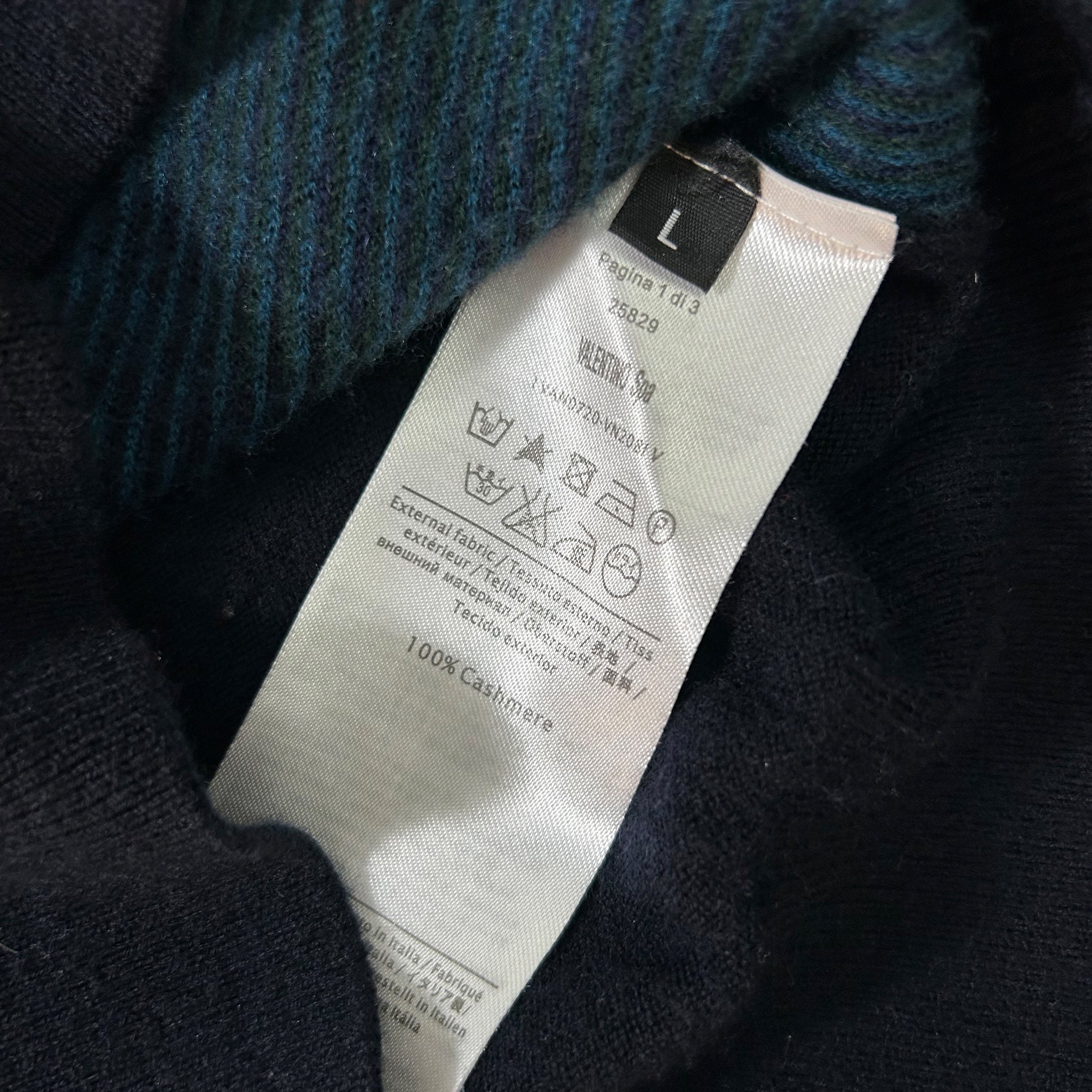 a close-up view of a clothing label, specifically a woolen sweater, with various symbols and text indicating the care instructions and material information.