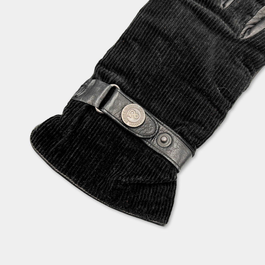 A close-up view of a black glove with a metal buckle and a black strap.