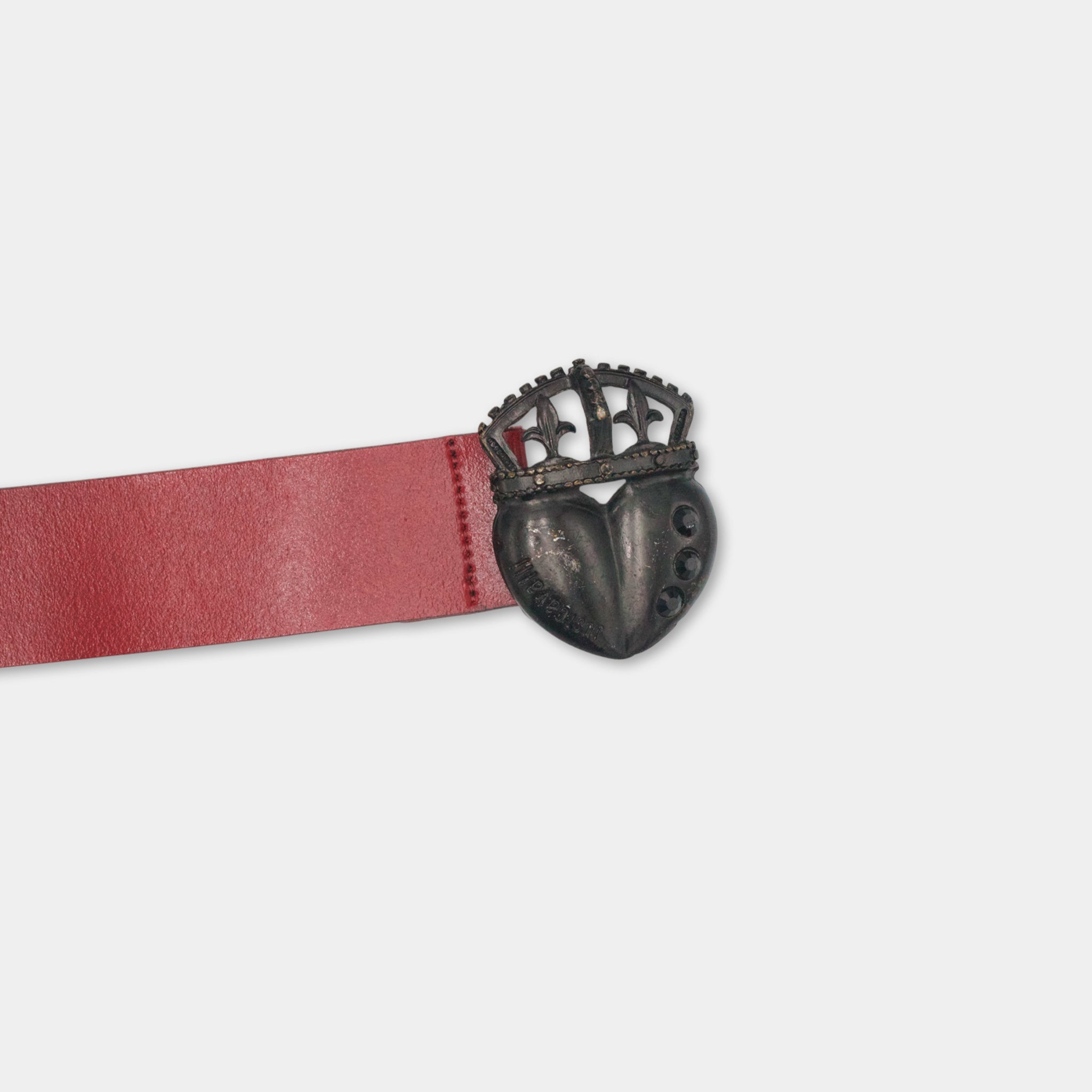 A red belt with a black metal heart-shaped buckle is shown against a white background.