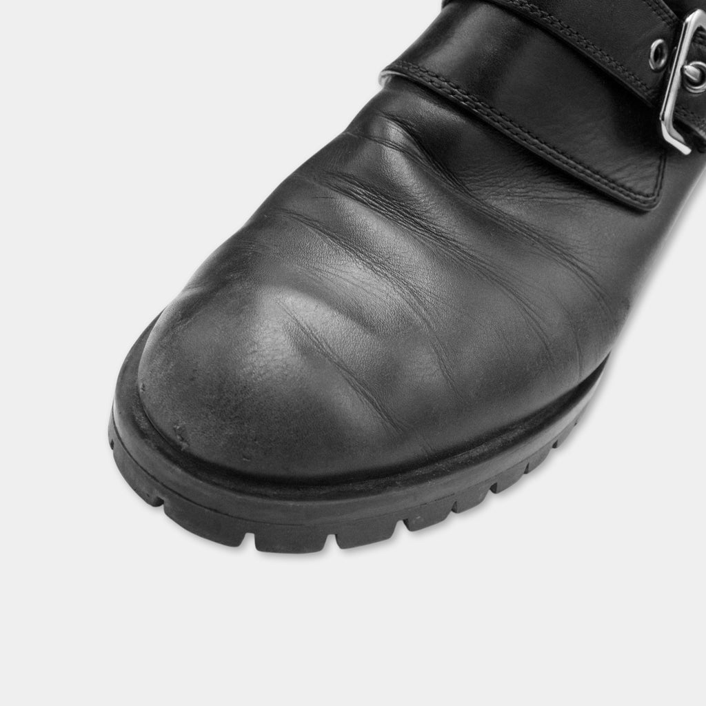 A close-up view of a black leather shoe with a buckle detail.