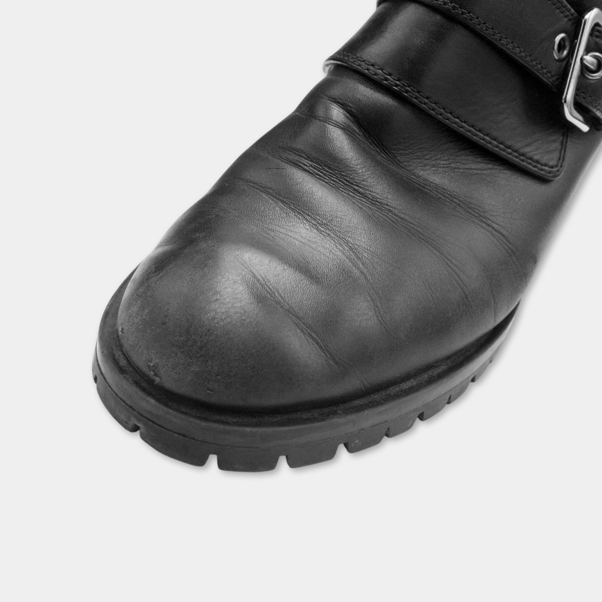 A close-up view of a black leather shoe with a buckle detail.