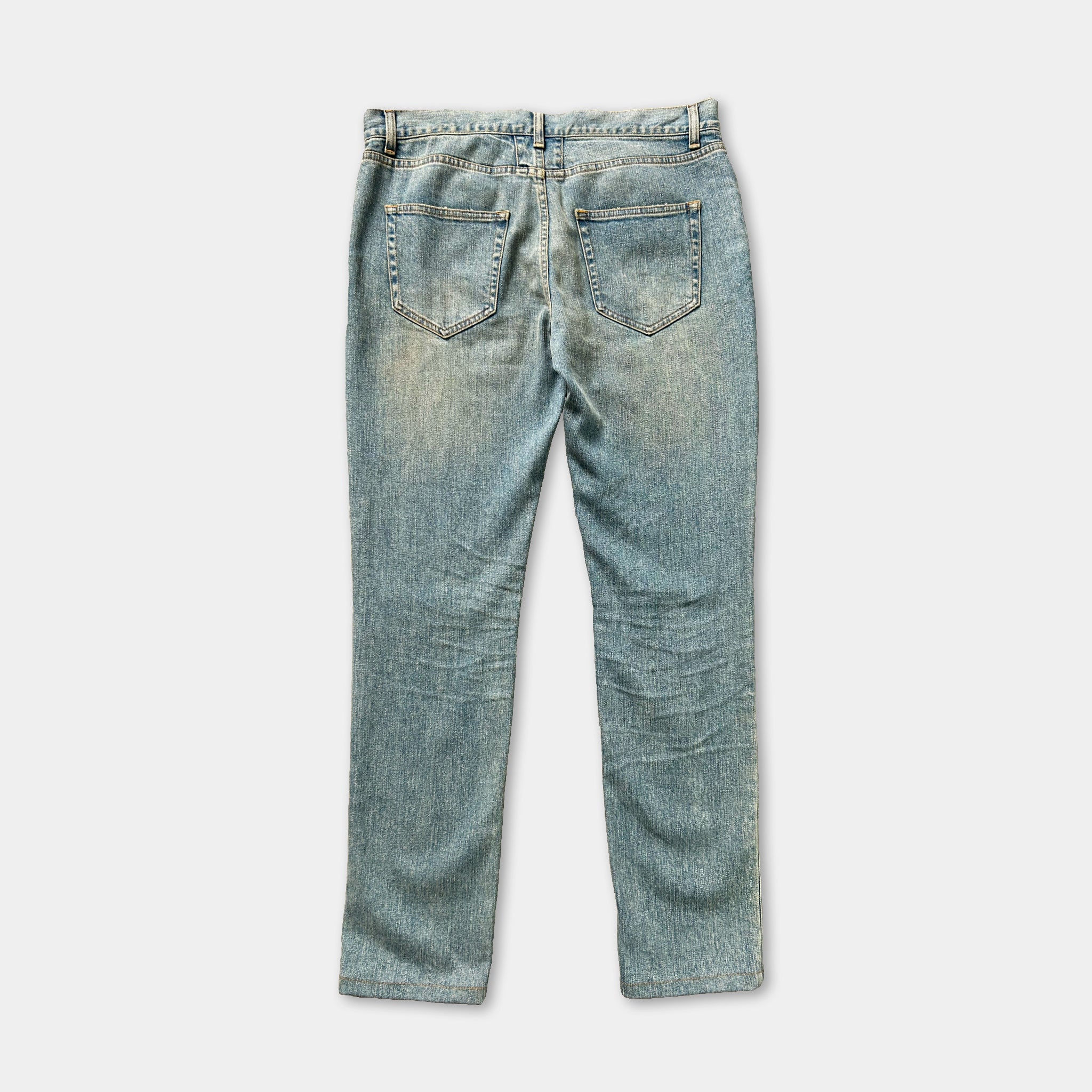 A pair of blue denim jeans with visible signs of wear and tear, including faded and distressed denim fabric.