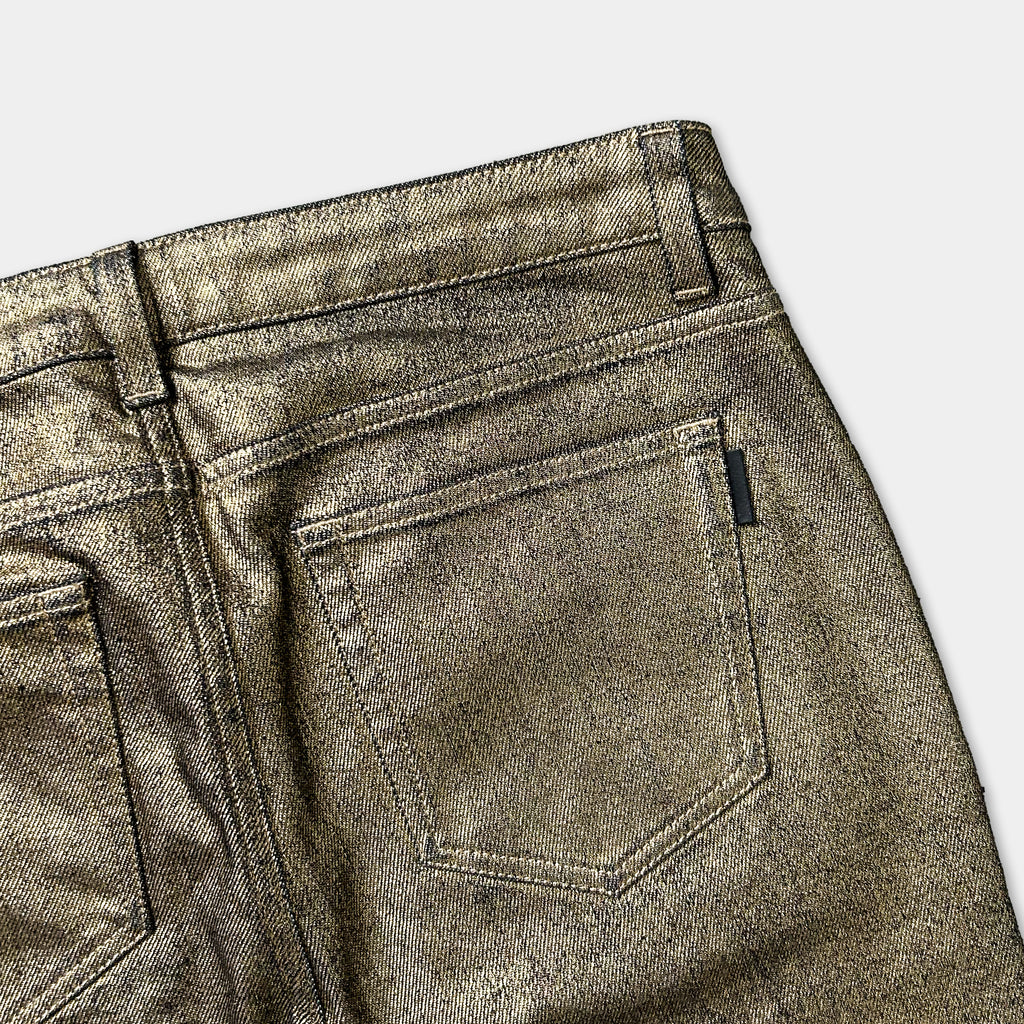 a close-up view of a pair of gold-colored, shiny jeans with a zipper pocket.