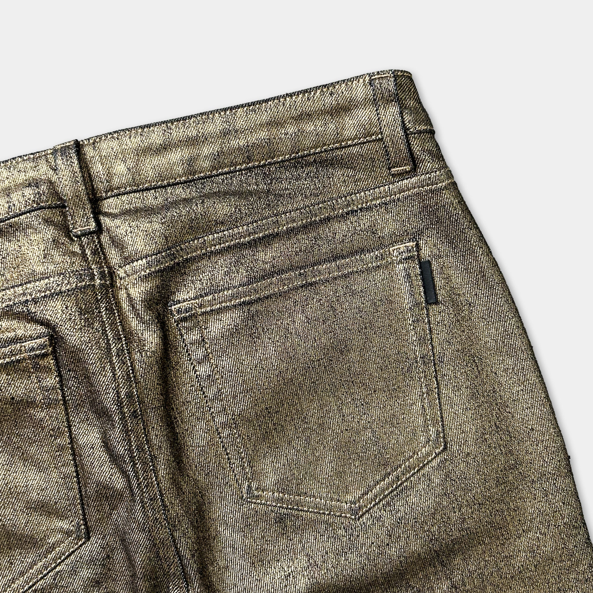 a close-up view of a pair of gold-colored, shiny jeans with a zipper pocket.