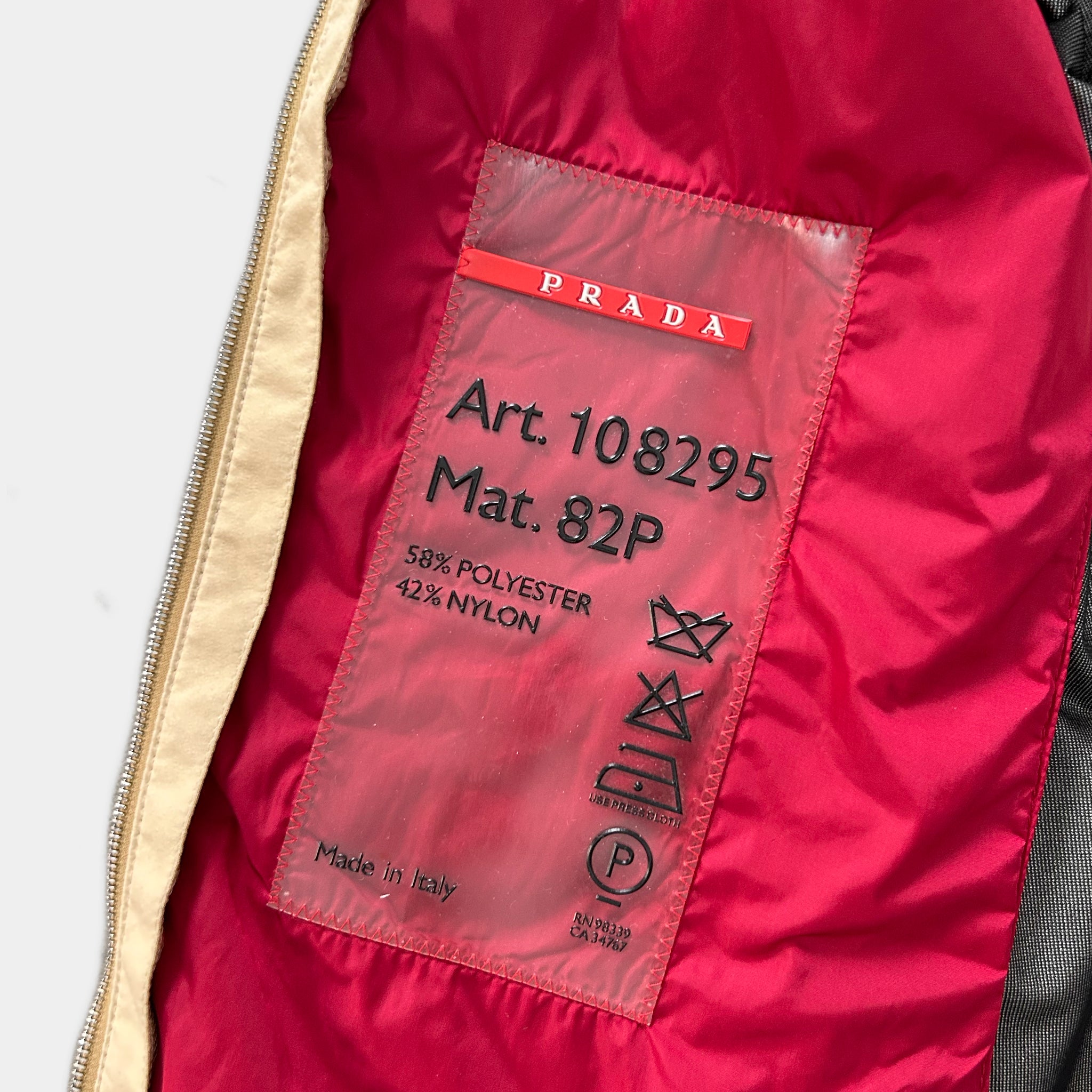 a close-up view of a red Prada jacket, with a label on the inside of the jacket.