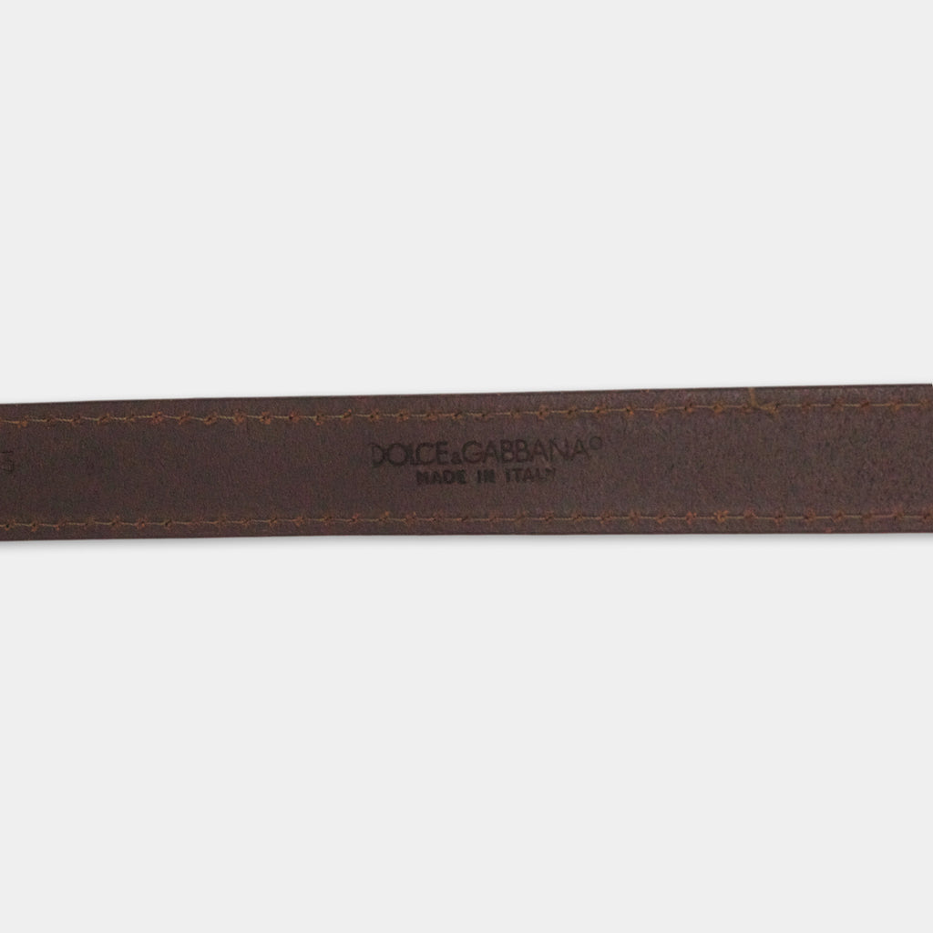 A close-up view of a brown leather belt with the brand name "Dolce & Gabbana" printed on it.