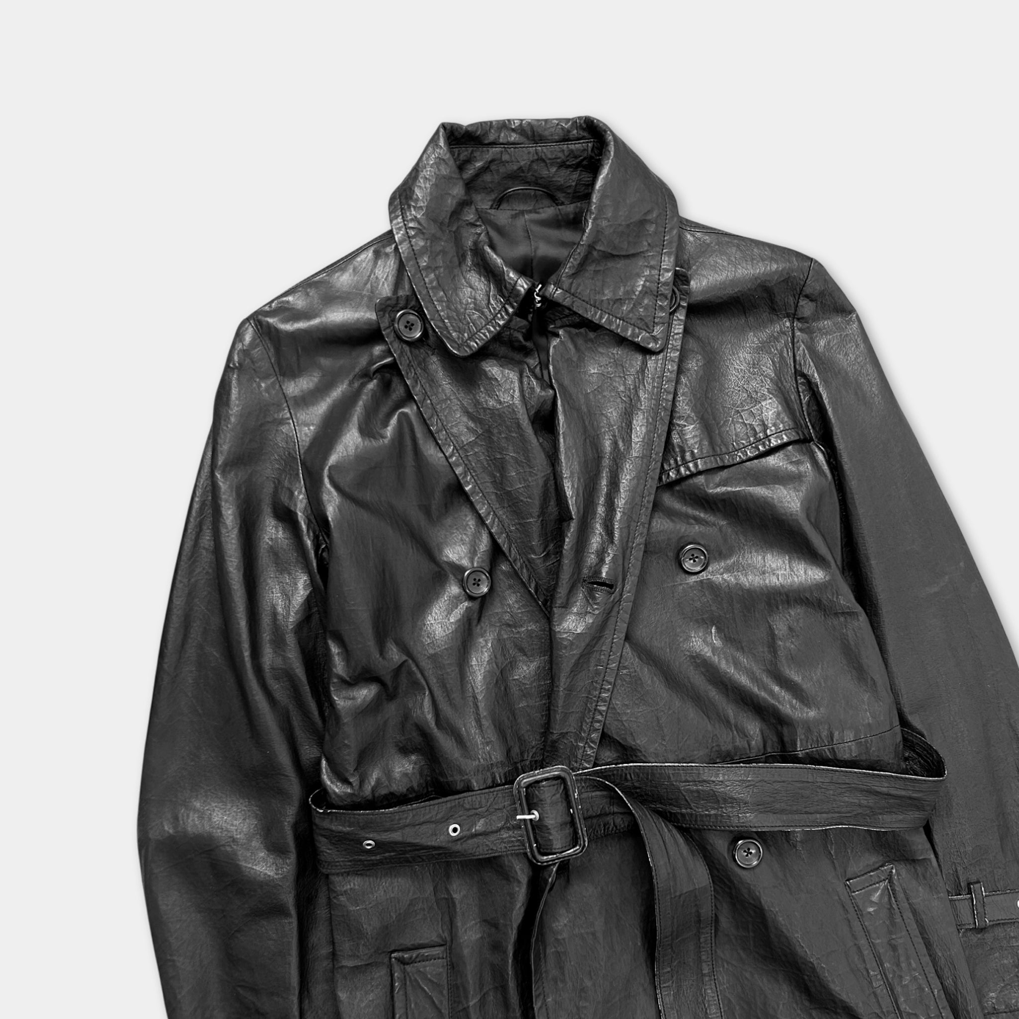 A black leather jacket with a double-breasted collar and a belt, displayed against a plain background.