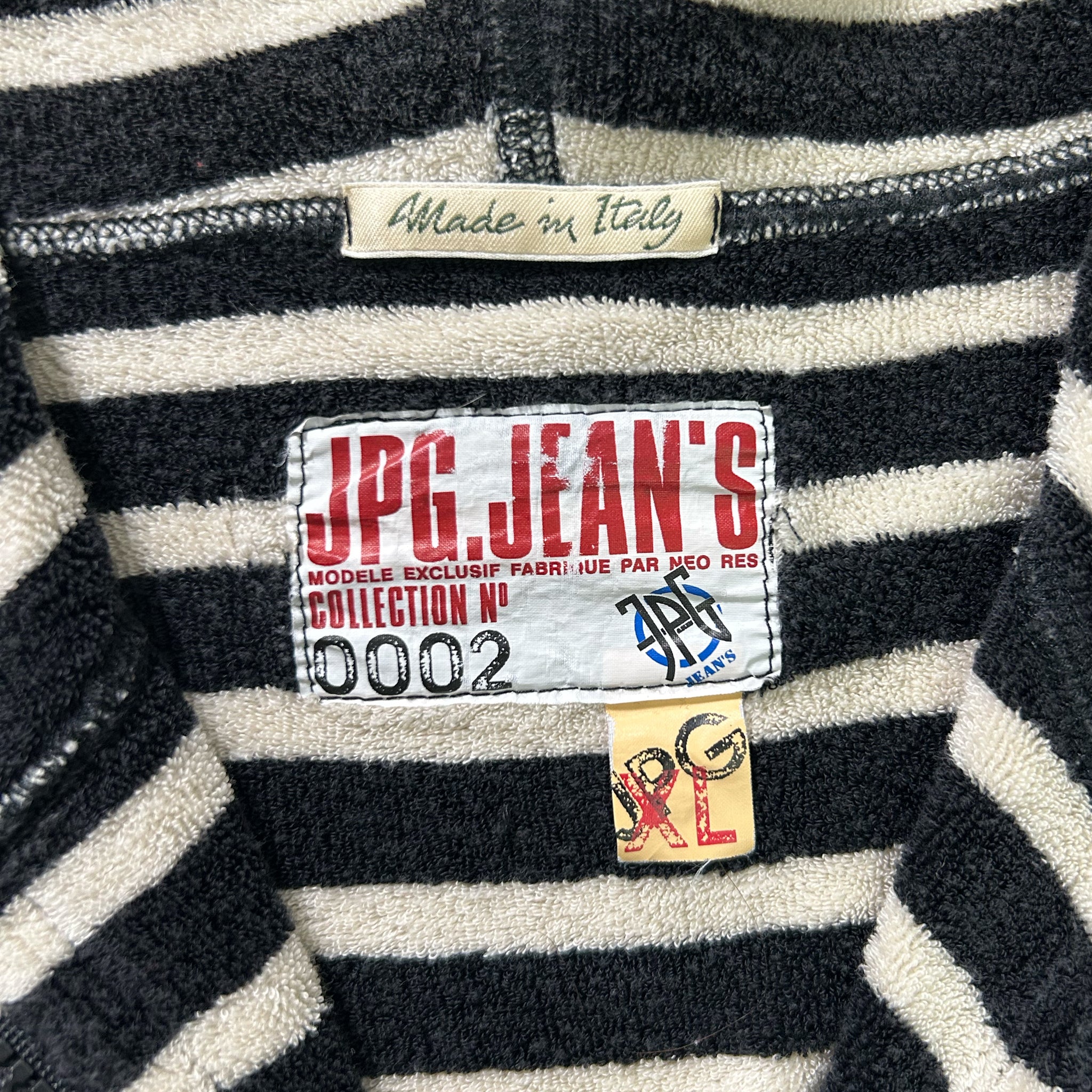 a close-up view of a black and white striped sweater, with a label on the collar that reads "Made in Italy".