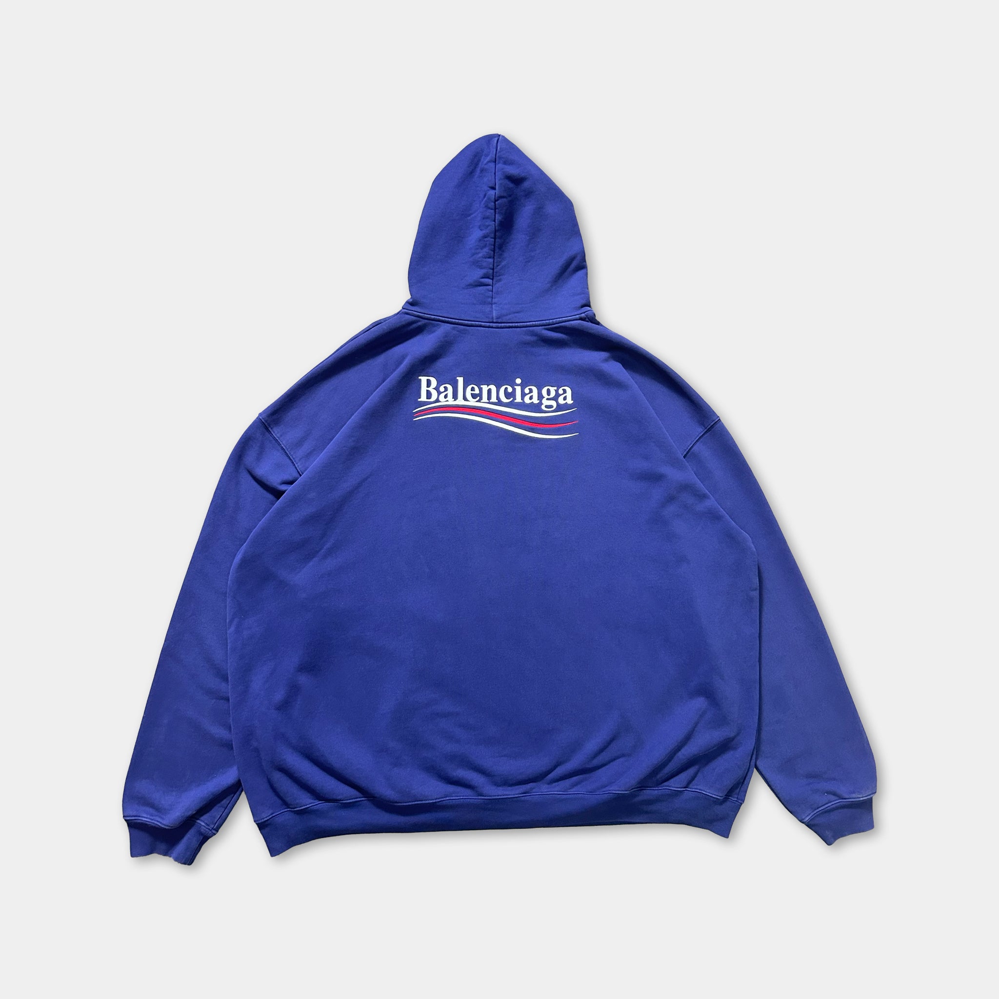 A blue hooded sweatshirt with the Balenciaga logo printed on the back.