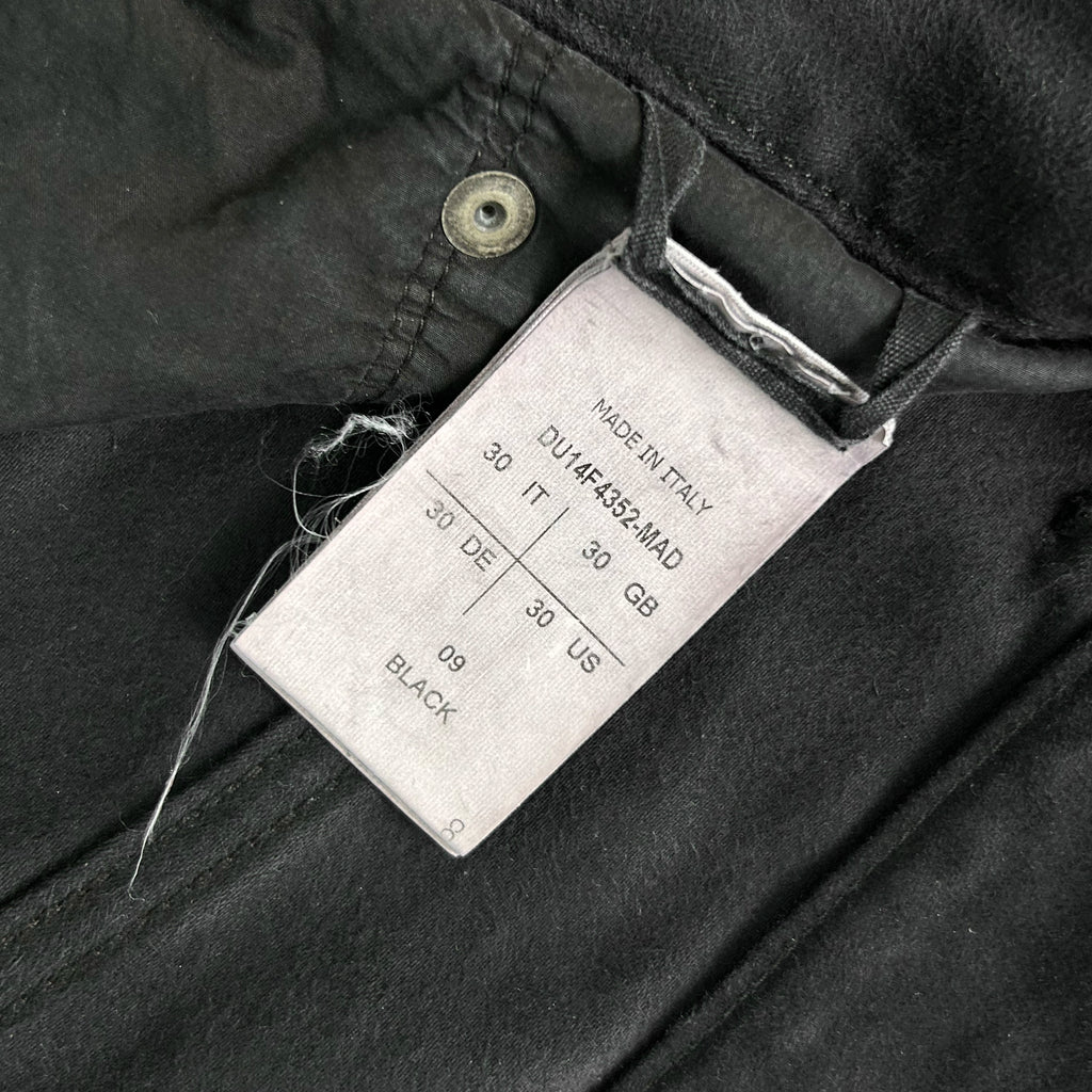 a close-up view of a black fabric, possibly a piece of clothing, with a label attached to it. The label appears to contain information about the fabric, such as the brand, size, and color.