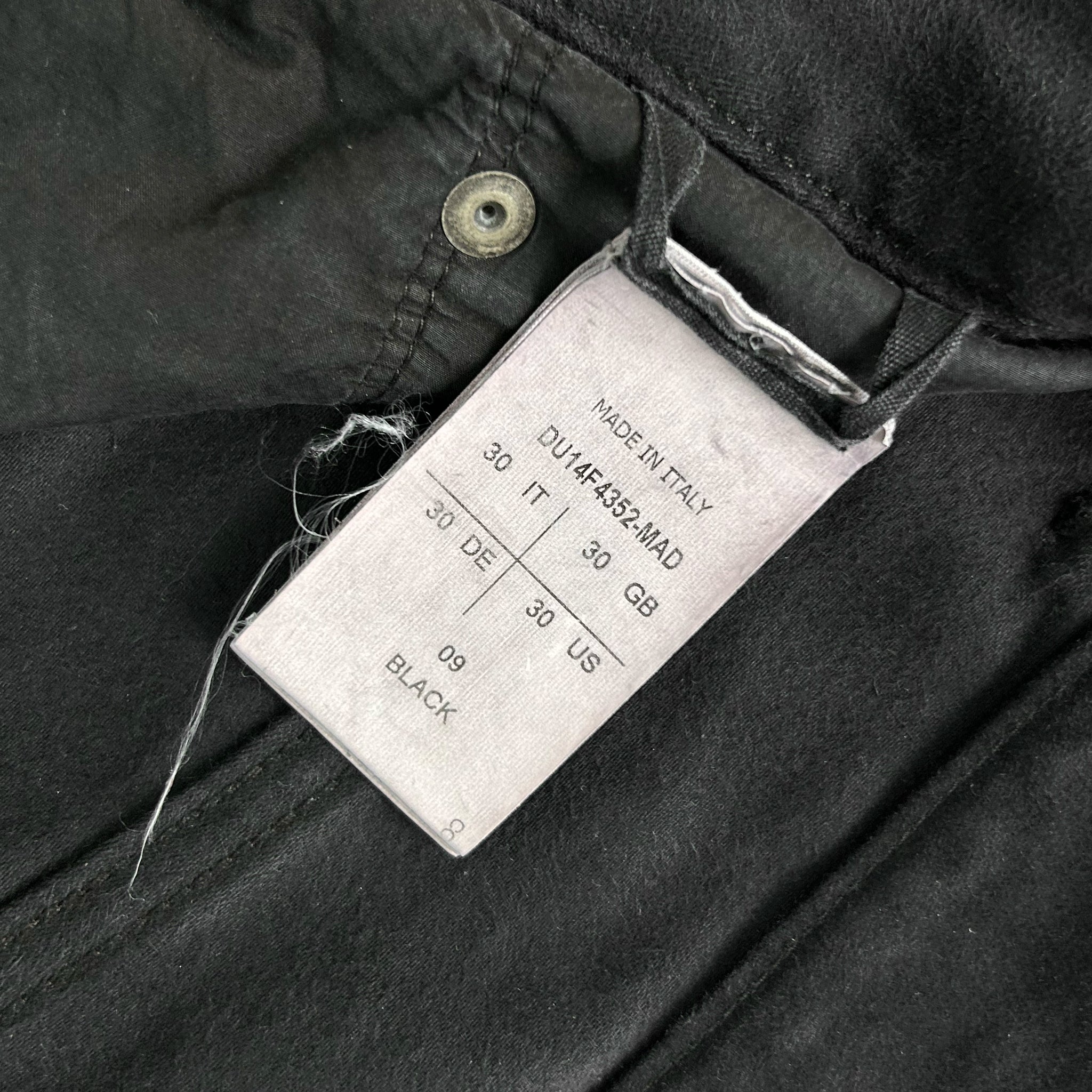 a close-up view of a black fabric, possibly a piece of clothing, with a label attached to it. The label appears to contain information about the fabric, such as the brand, size, and color.