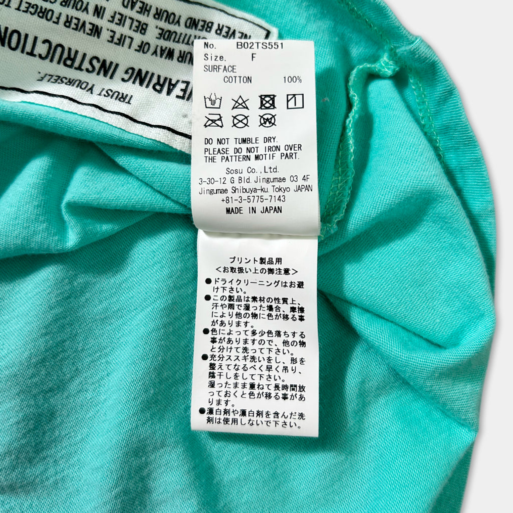 a close-up of a turquoise fabric with a label attached to it, which contains text in Japanese.