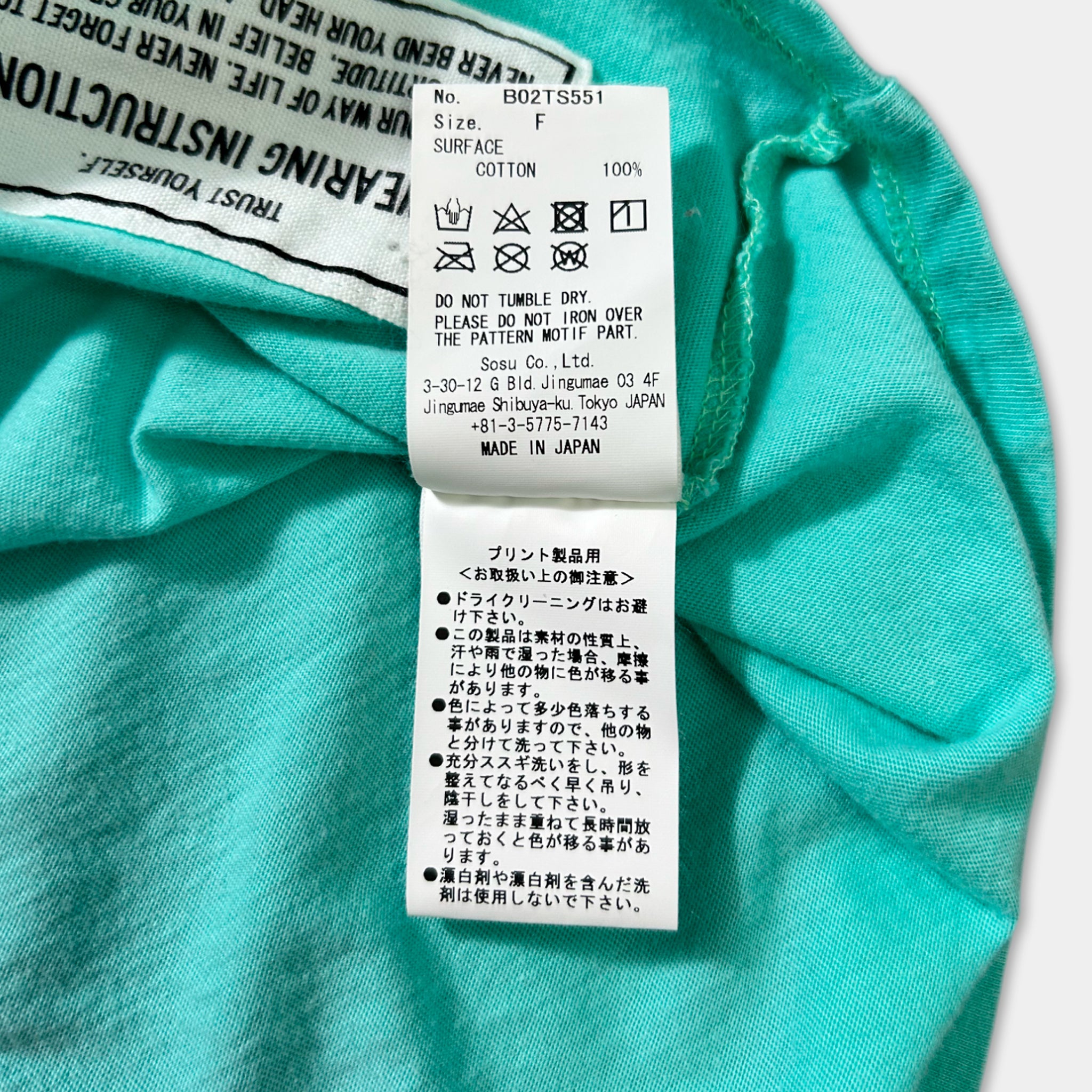 a close-up of a turquoise fabric with a label attached to it, which contains text in Japanese.