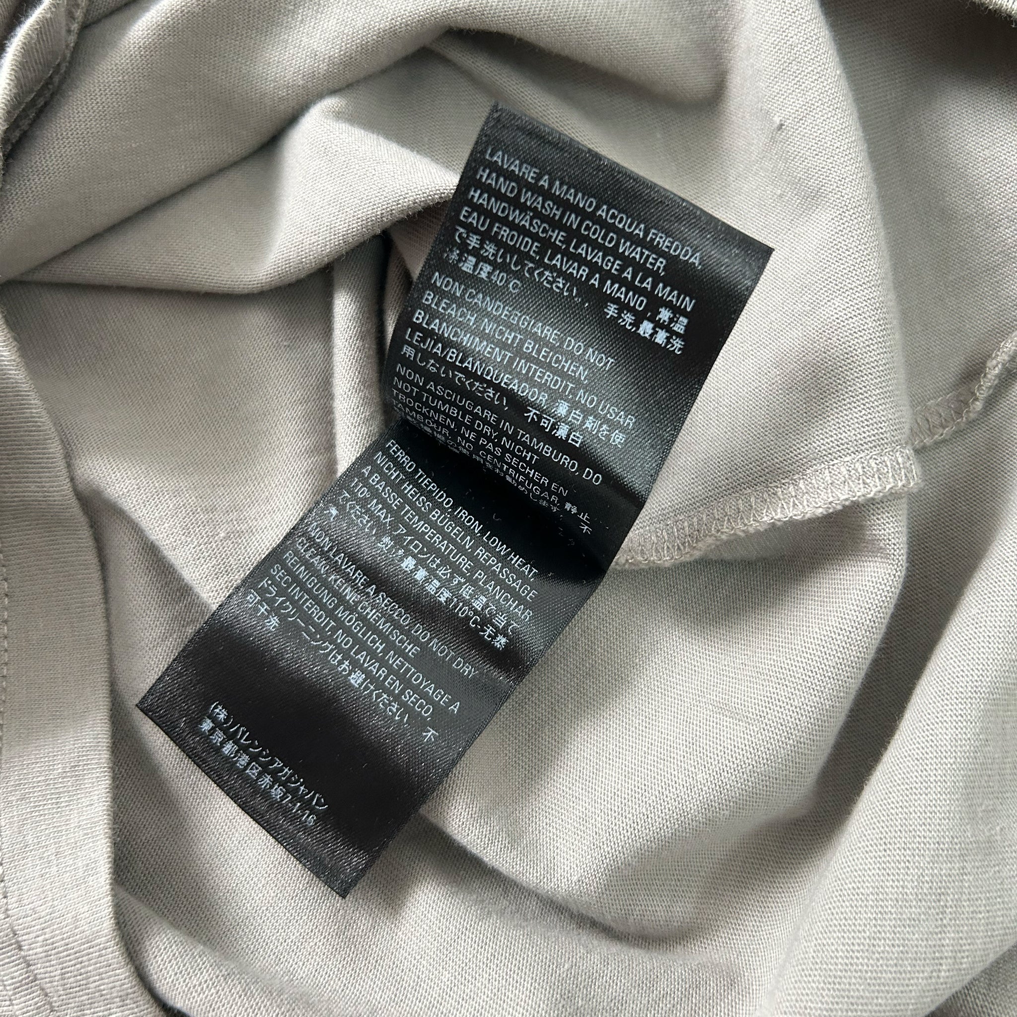 a close-up view of a black and white label on a light-colored fabric, likely a piece of clothing.