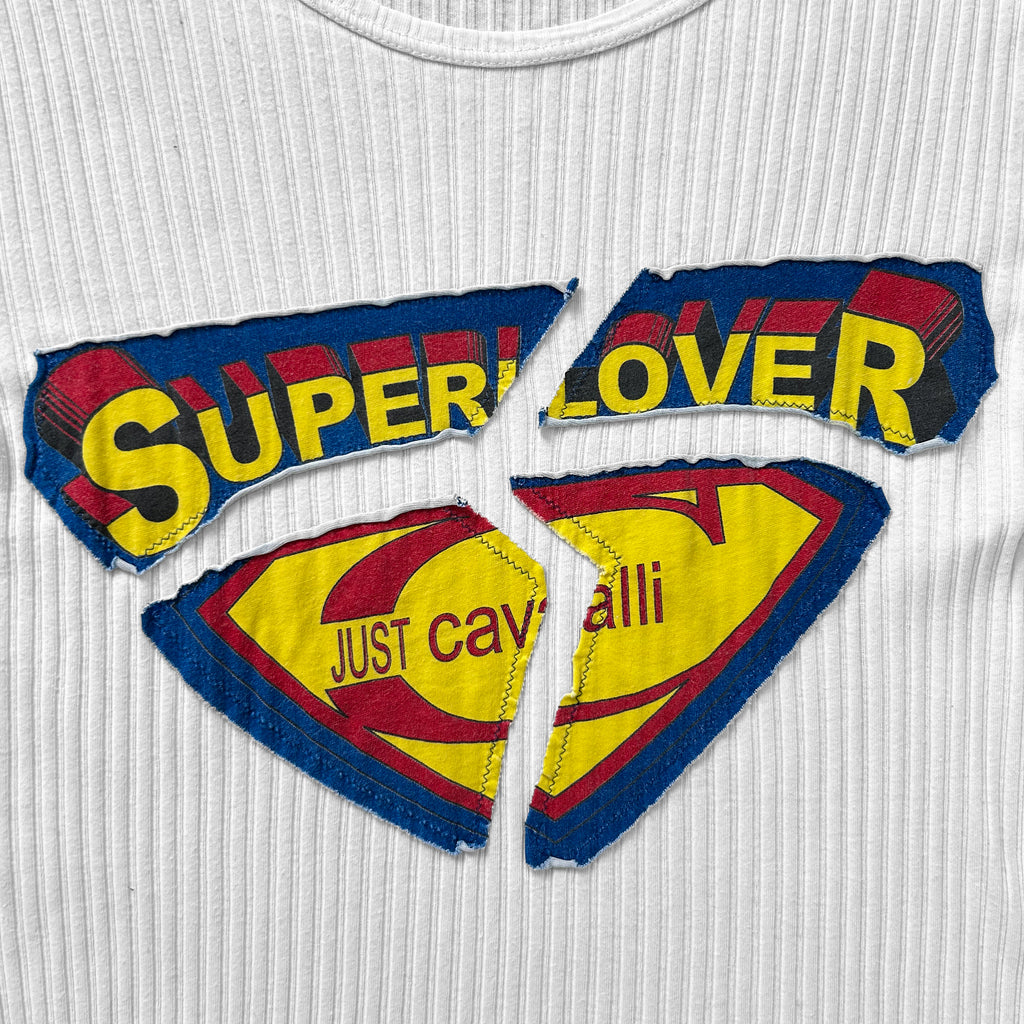 a white t-shirt with a large, colorful graphic design on it. The design includes the words "SUPERLOVER" and "JUST CAVING" in a stylized font, along with a yellow and red color scheme. The design is broken into three pieces, with the word "SUPERLOVER" being the most prominent.