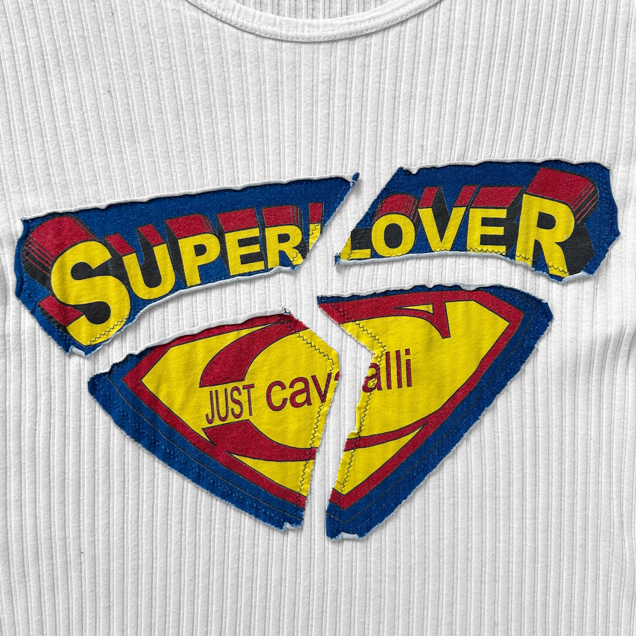 a white t-shirt with a large, colorful graphic design on it. The design includes the words "SUPERLOVER" and "JUST CAVING" in a stylized font, along with a yellow and red color scheme. The design is broken into three pieces, with the word "SUPERLOVER" being the most prominent.
