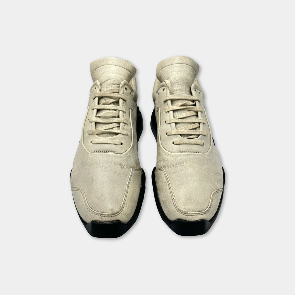 A pair of tan-colored sneakers with black soles and laces.