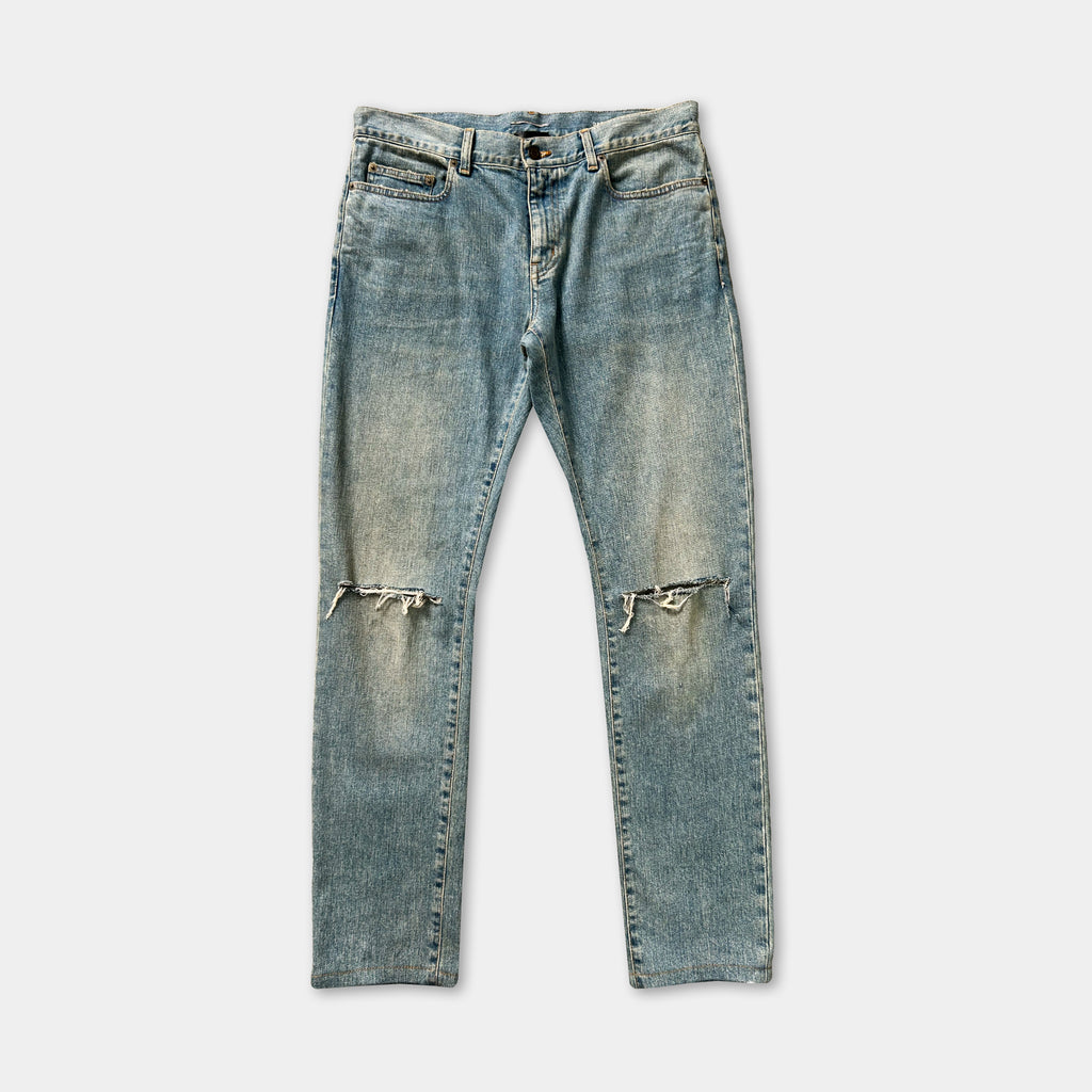 A pair of blue denim jeans with visible holes and frayed edges, suggesting they are well-worn.