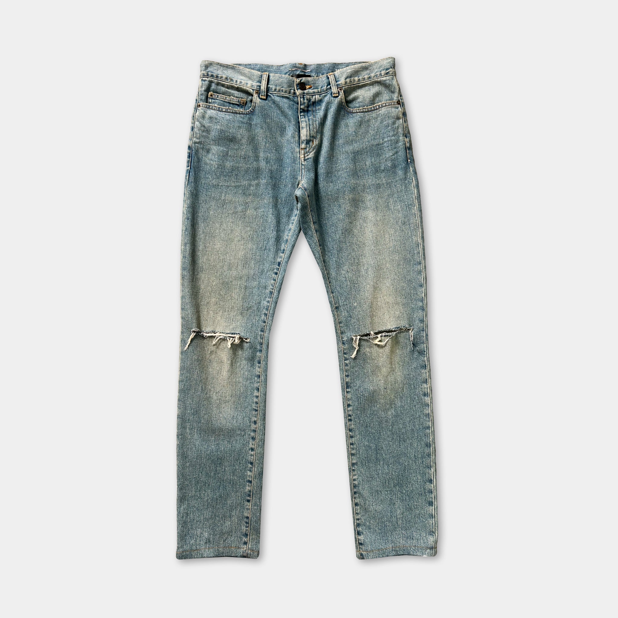 A pair of blue denim jeans with visible holes and frayed edges, suggesting they are well-worn.