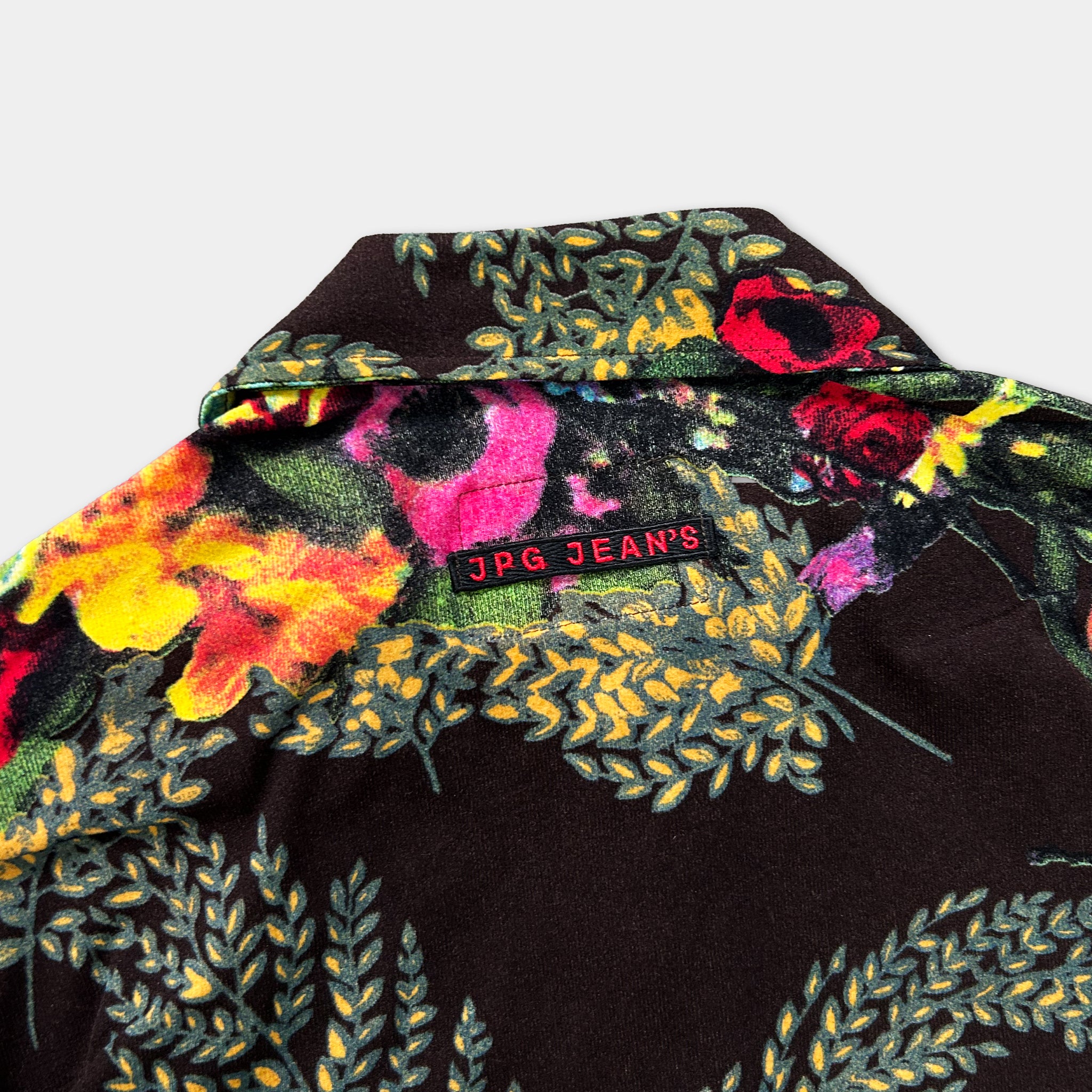 a close-up view of a colorful, patterned shirt with a collar and a red label on the back.