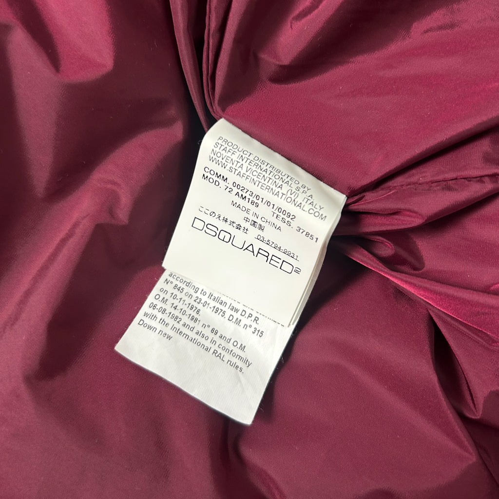a close-up view of a red fabric, possibly a piece of clothing, with a label attached to it. The label appears to be a product label or tag, providing information about the product.