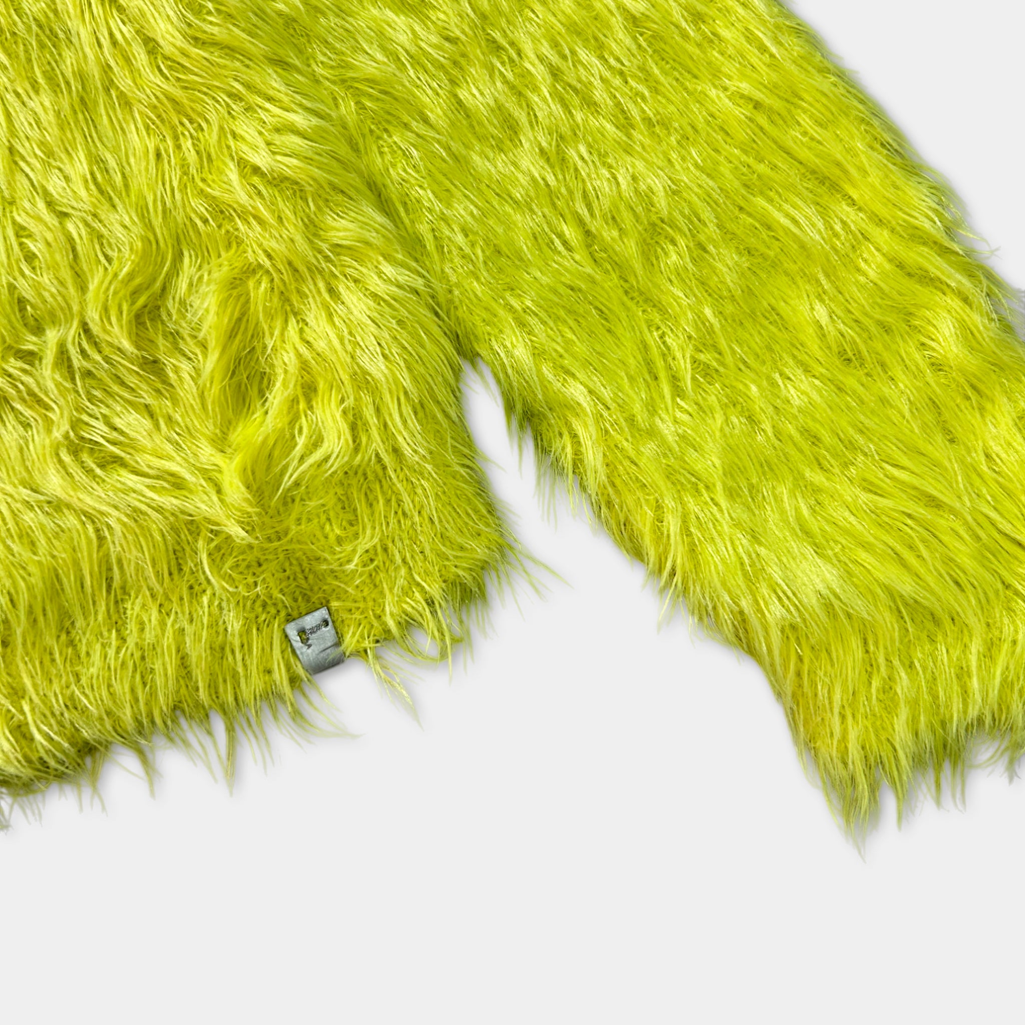 A close-up image of a bright yellow, furry fabric, possibly a jacket or blanket, with a small tag or label attached to it.