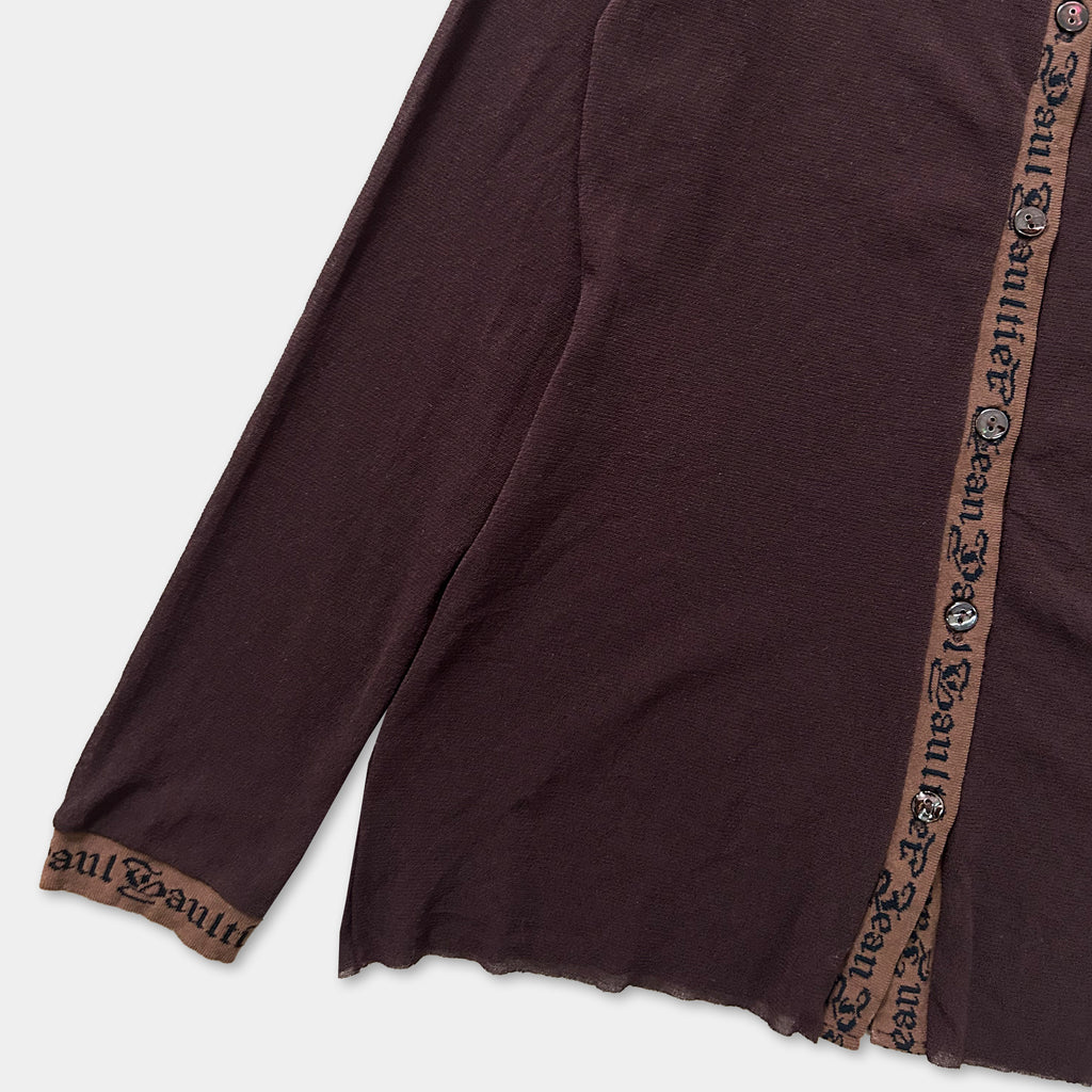 A close-up view of a dark brown long-sleeved garment with a brown trim, featuring a repeating pattern of text or design on the fabric.