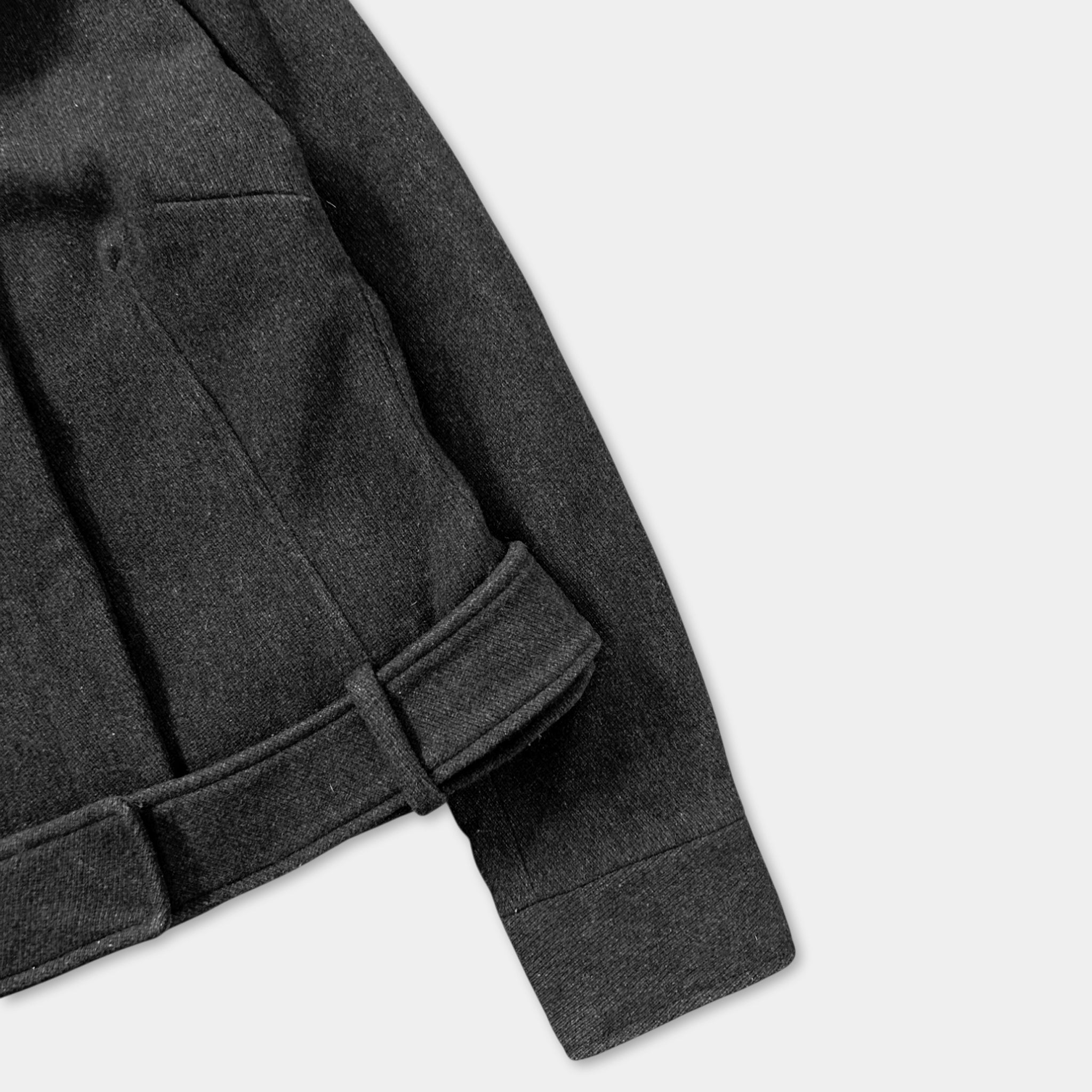 A close-up view of a dark grey jacket with a belt, showing the details of the jacket's design.