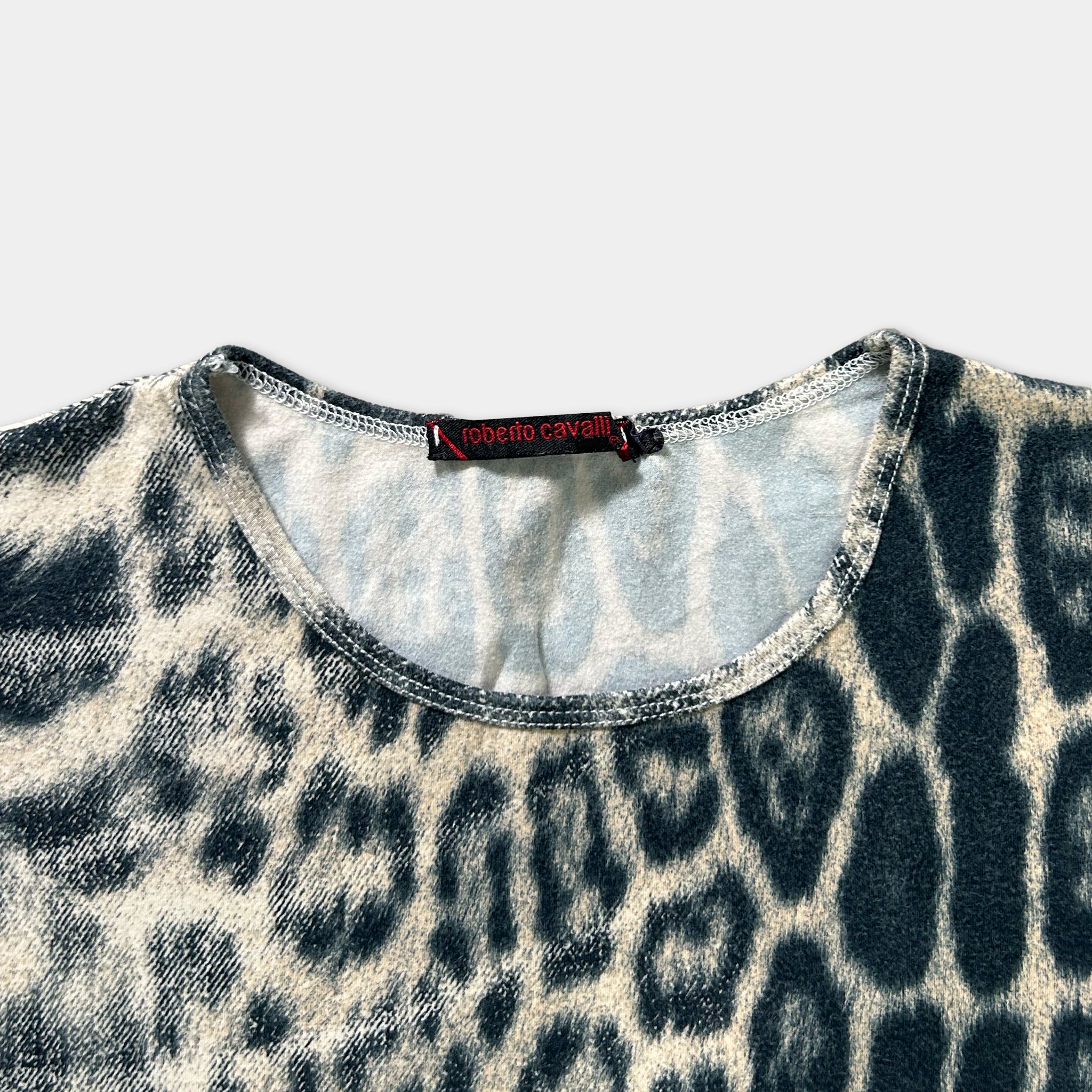 A close-up view of a leopard print shirt with a red label on the collar.
