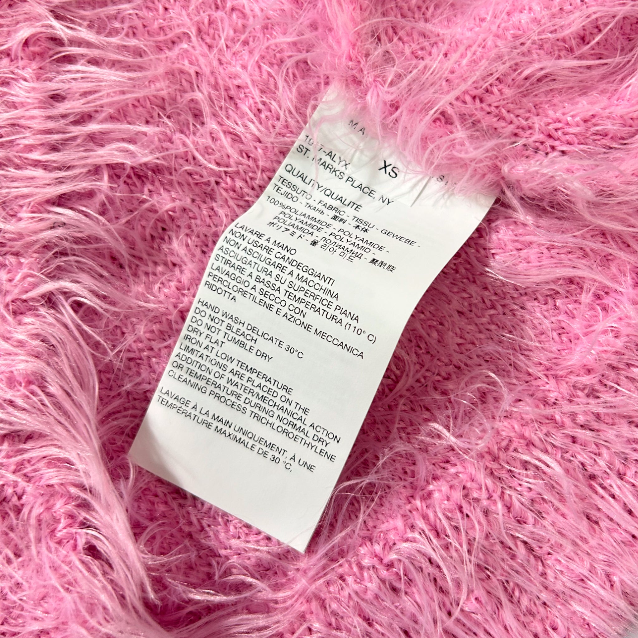 a close-up of a white label with text on a pink fuzzy surface.