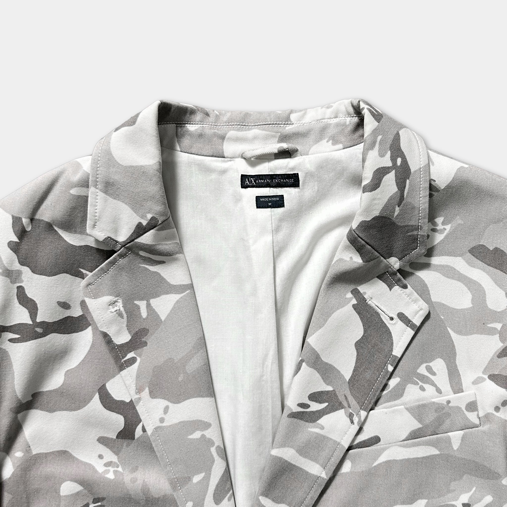 A close-up view of a camouflage-patterned jacket with a white lining.