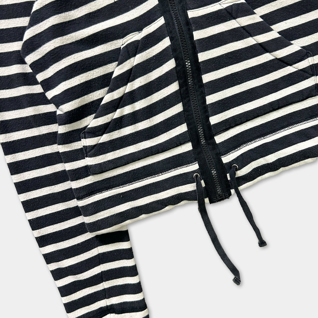 A close-up view of a black and white striped hoodie with a zipper and drawstring.